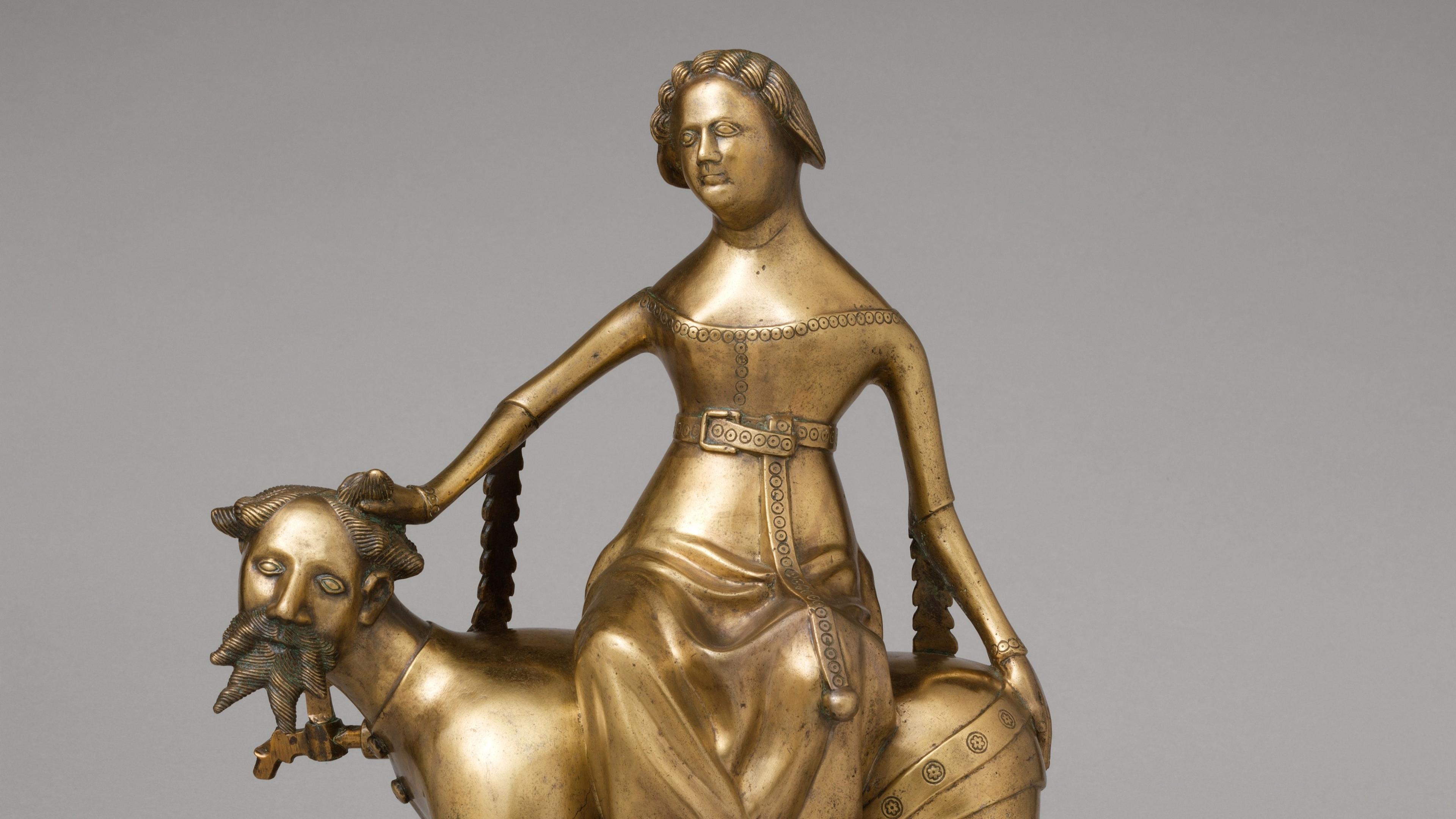 A sculpture of a woman in a dress witting atop a bearded man on all fours
