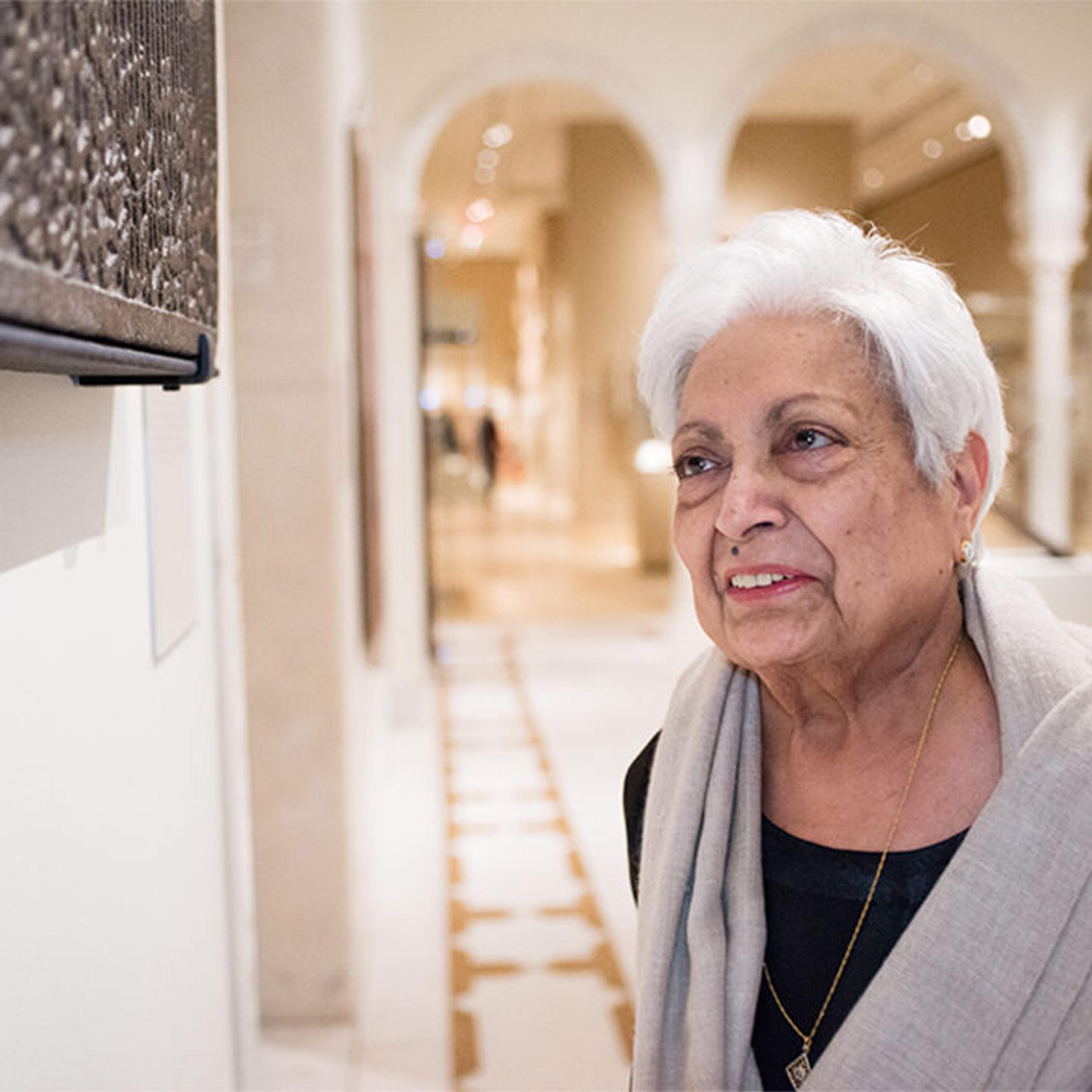 The artist Zarina looks at a work of Arabic script
