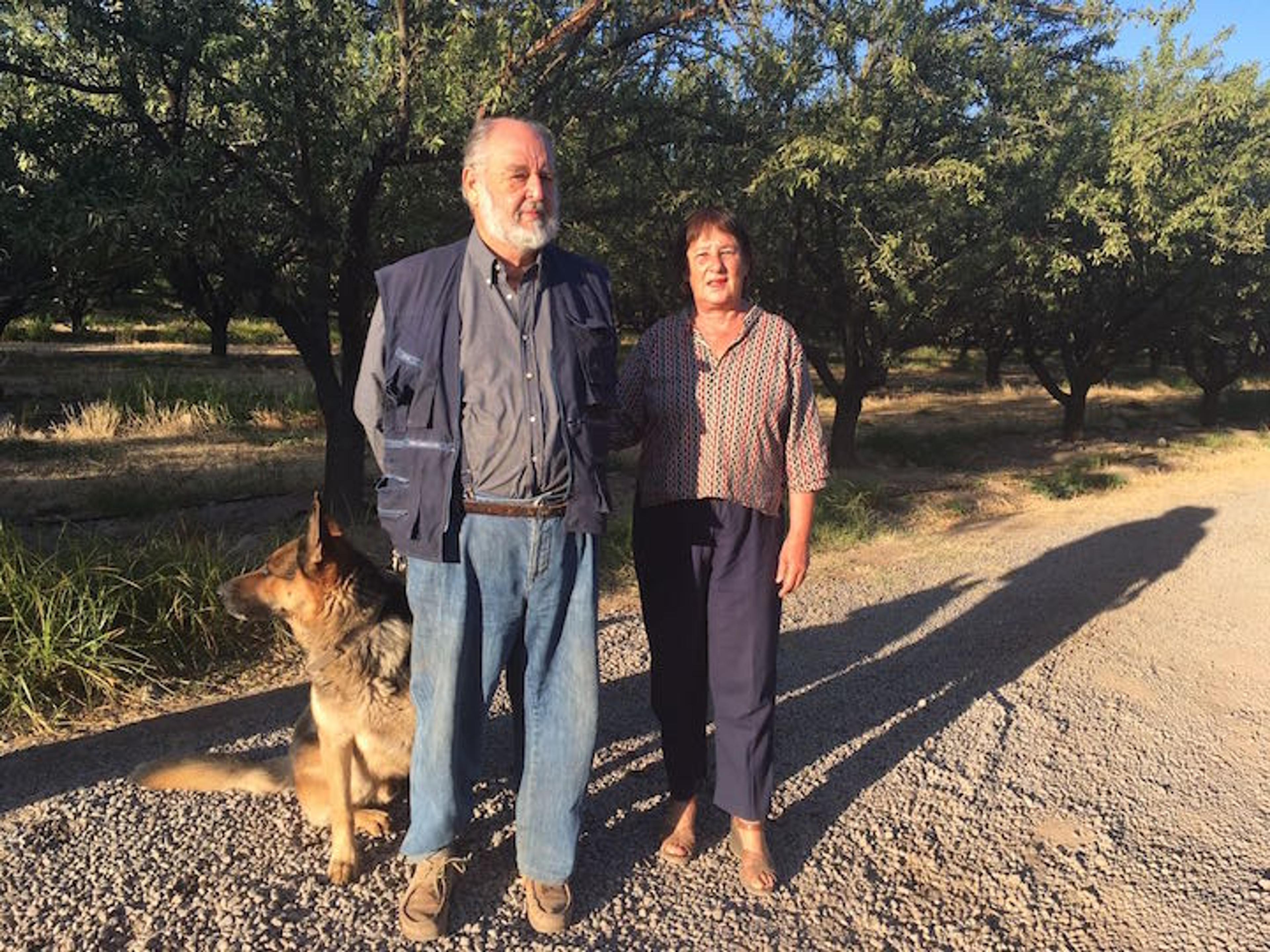 Two farmers and their German shepherd on an orchard in Chile
