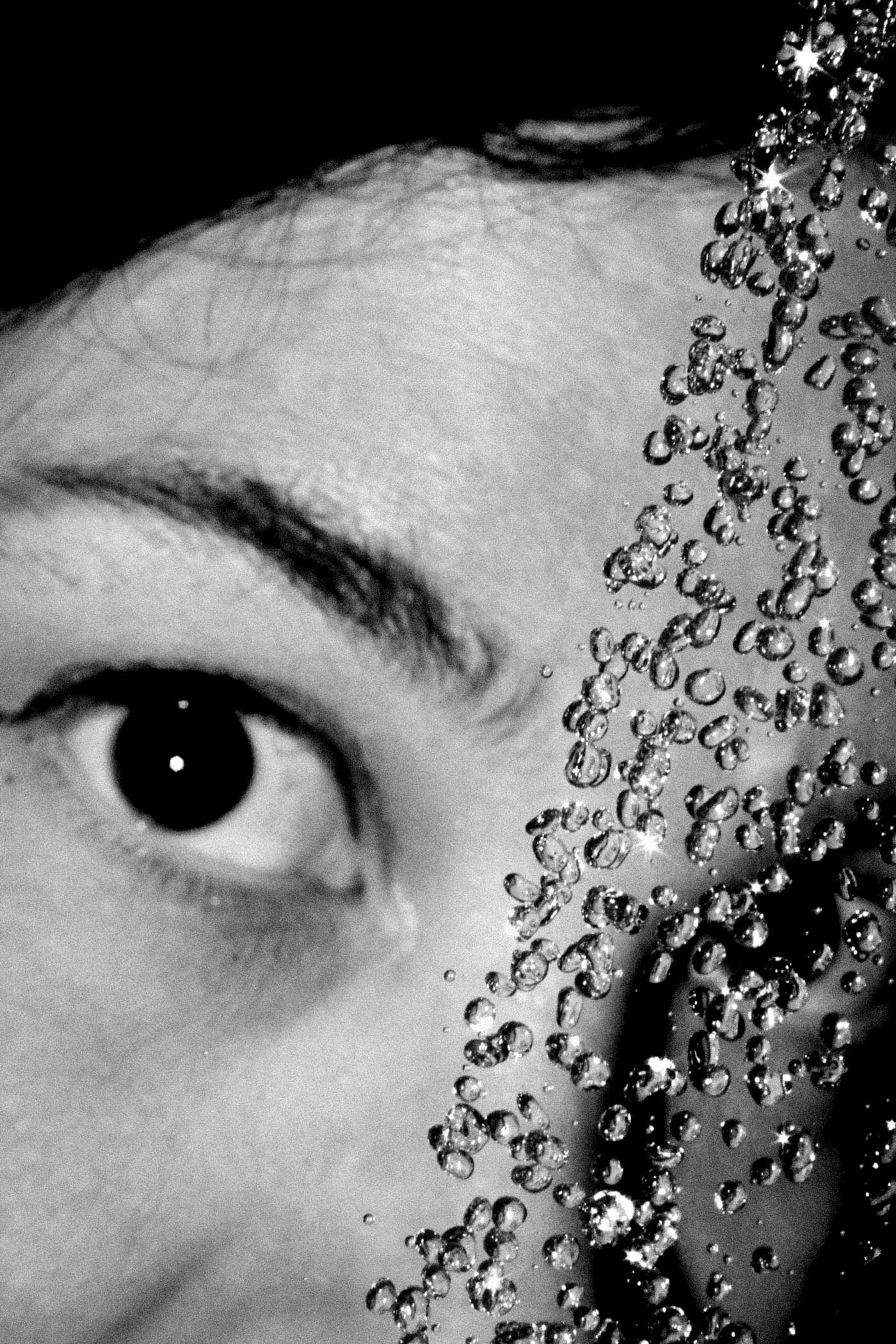 Close up photograph of an eye behind a spray of water.