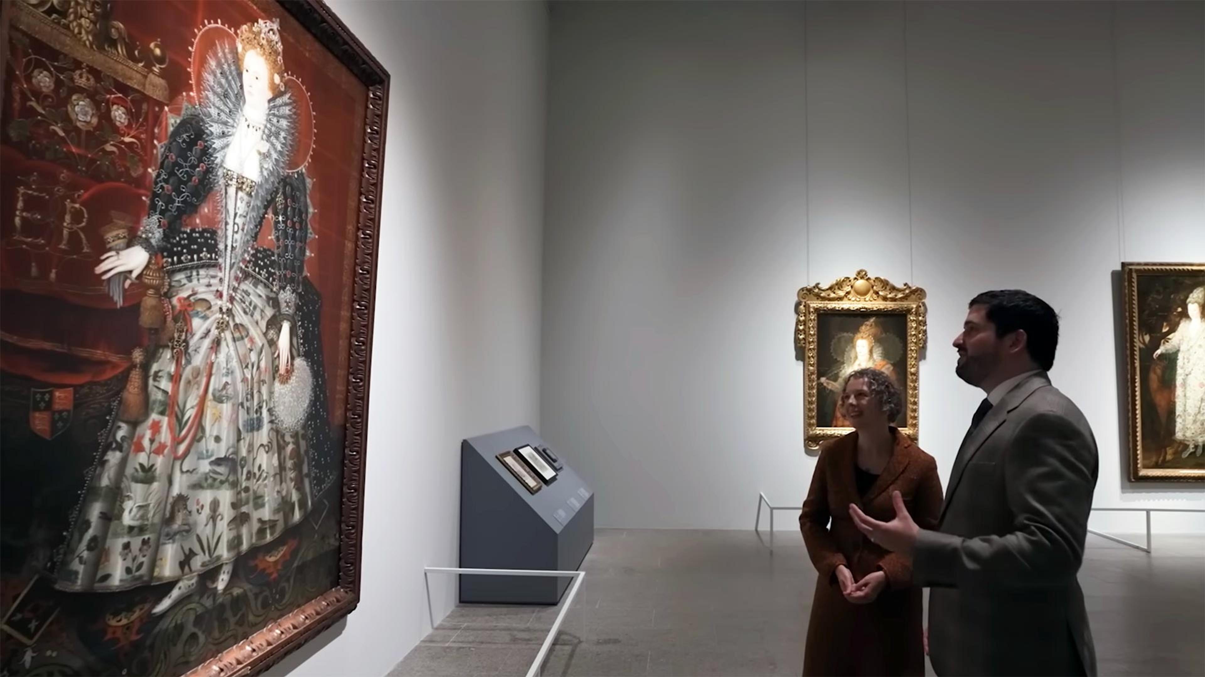 Curators Lizzie Cleland and Adam Eaker in the Tudors exhibition looking at a painted portrait of Queen Elizabeth I