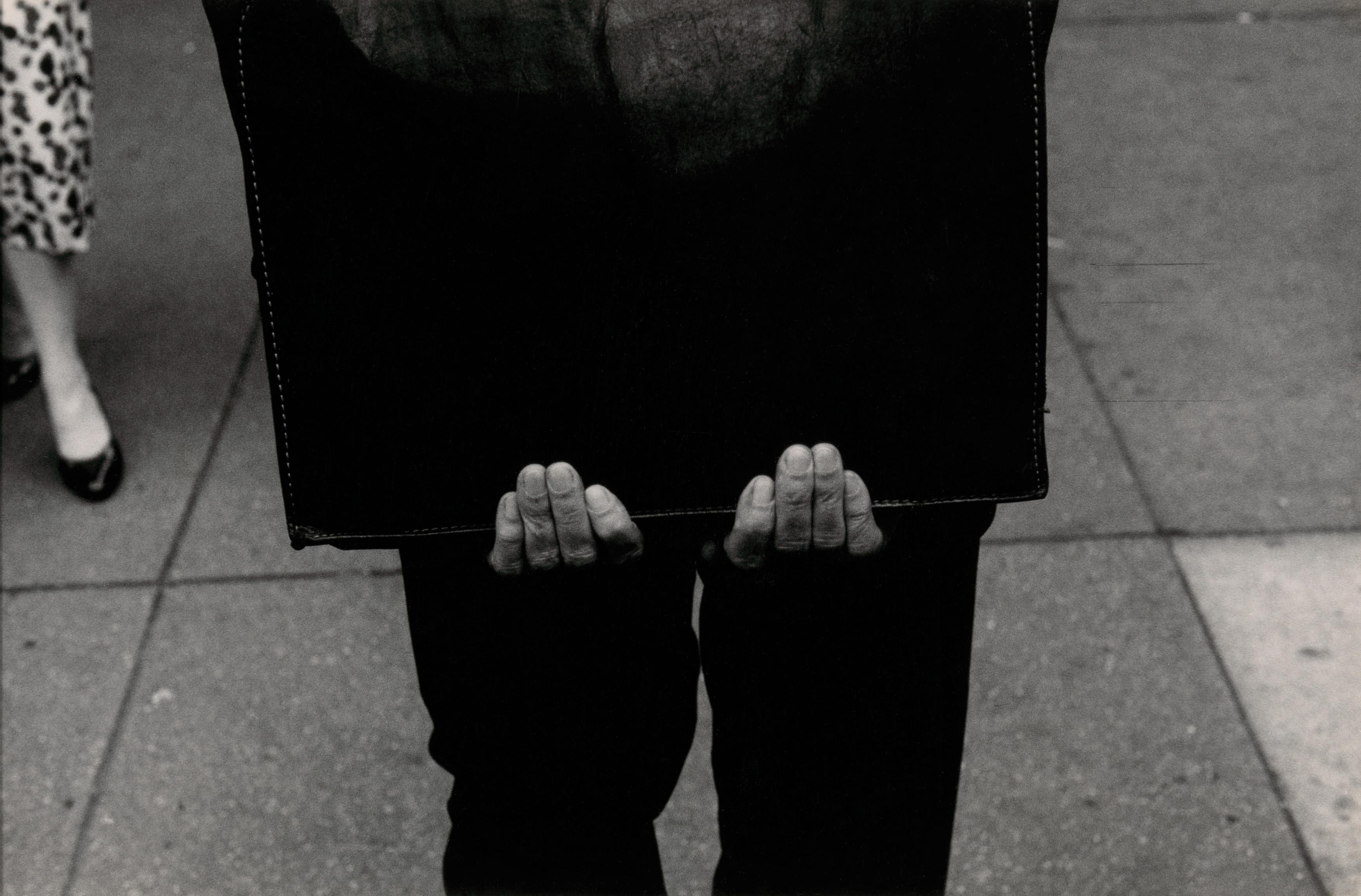 Black and white photograph of a man's hands holding a black portfolio.
