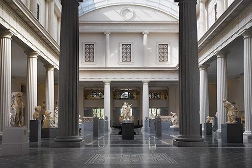 A very large gallery enclosed by a colonnade and filled with with sculptures from ancient Rome
