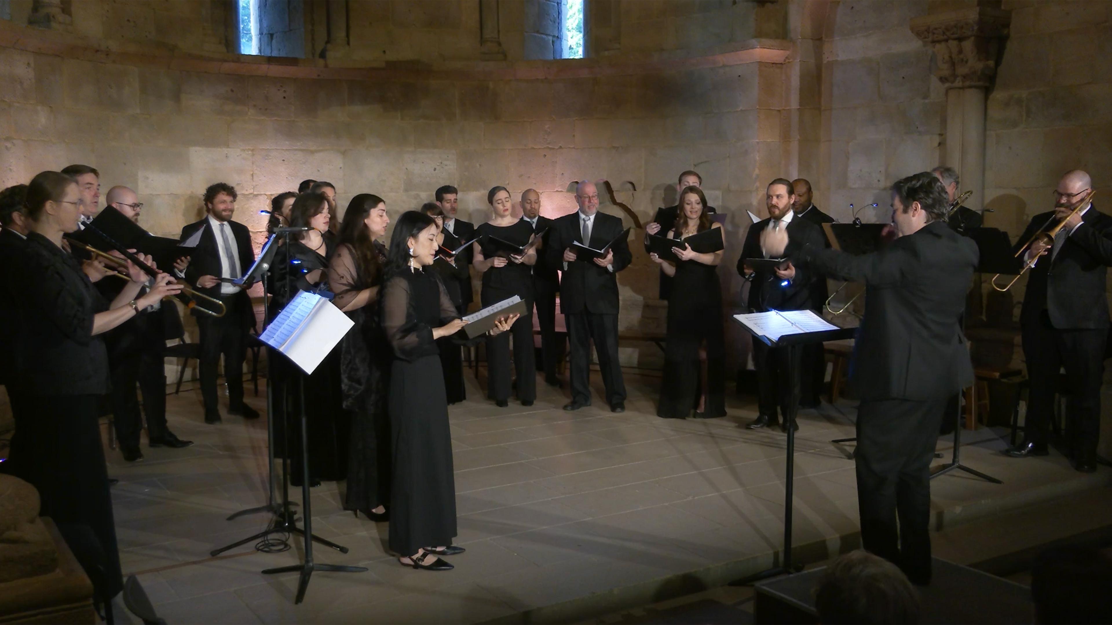 Singers and musicians, all dressed in black, in performance in the Fuentidueña Chapel
