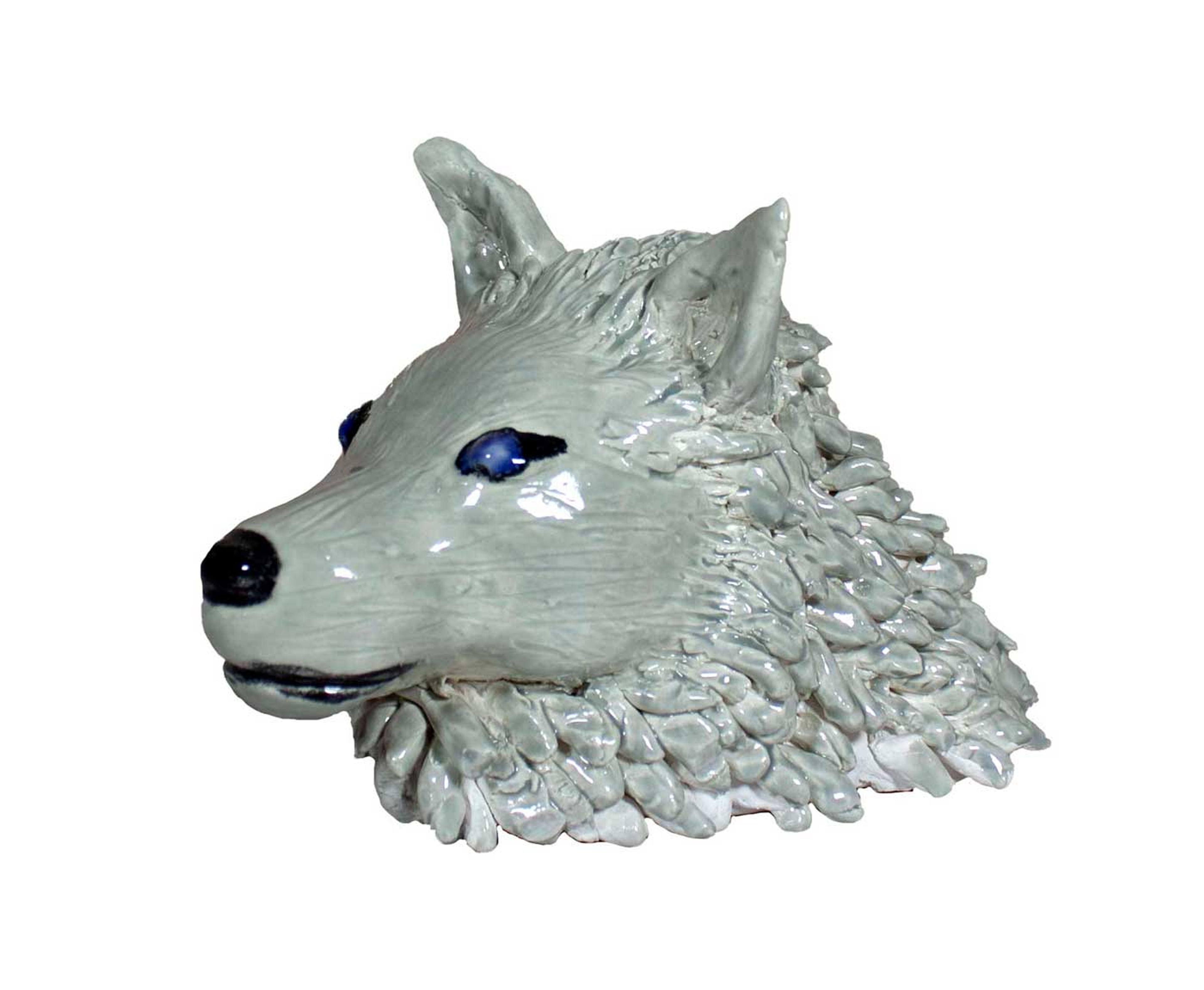 Sculpture of a white wolf's head with blue eyes.