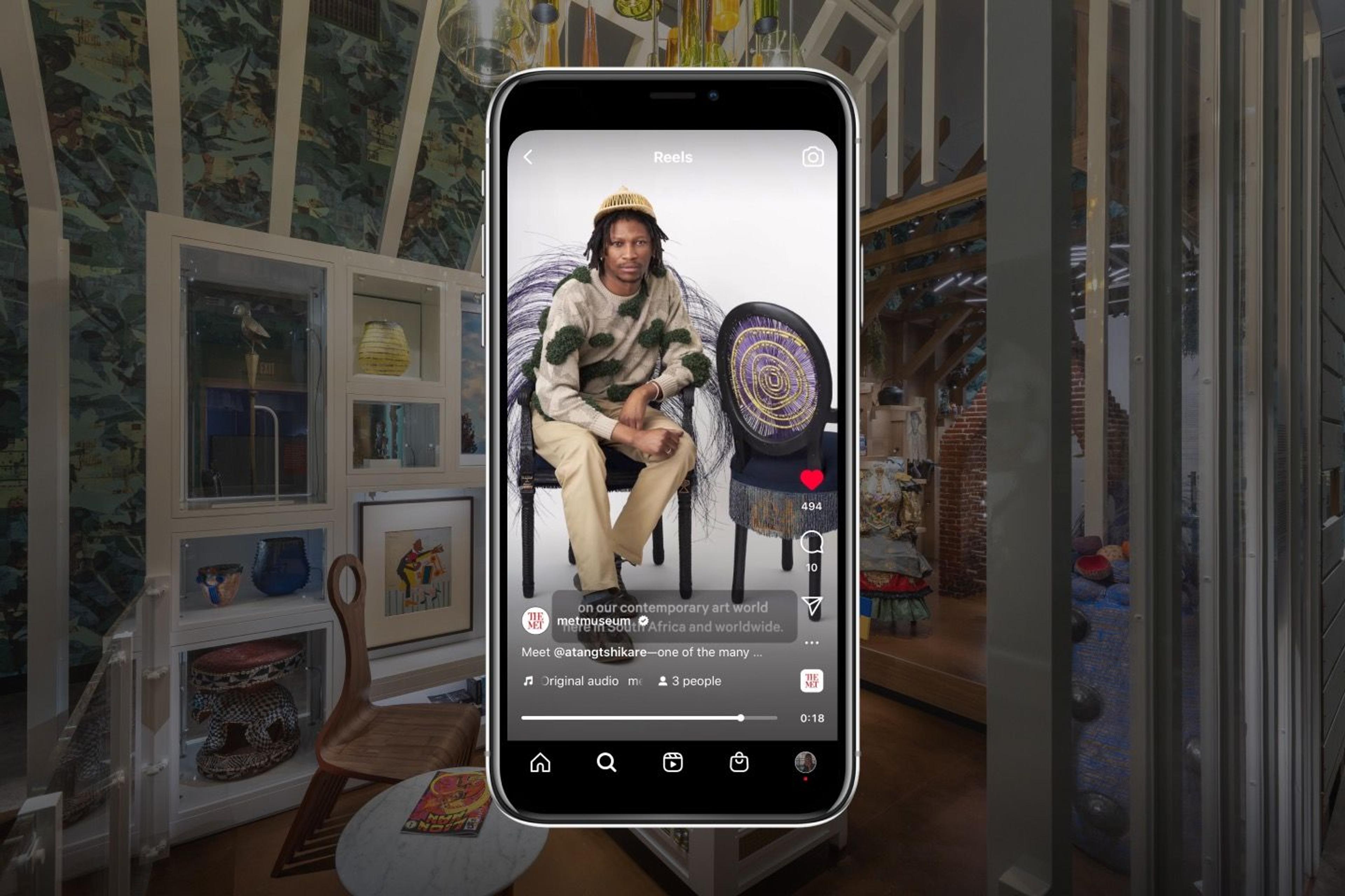 The artist Atang Tshikare is visible on a cell phone before a blurred backdrop of the Afrofuturist period room currently on view at The Met.