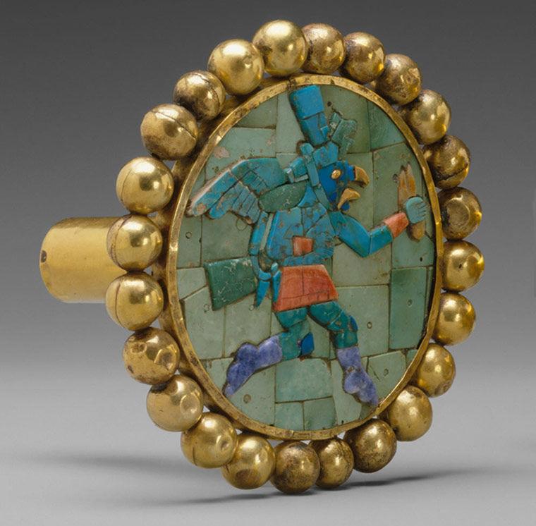 One of the ear ornaments from the pair. The ear ornament is made of many types of stone that forms a mosaic.