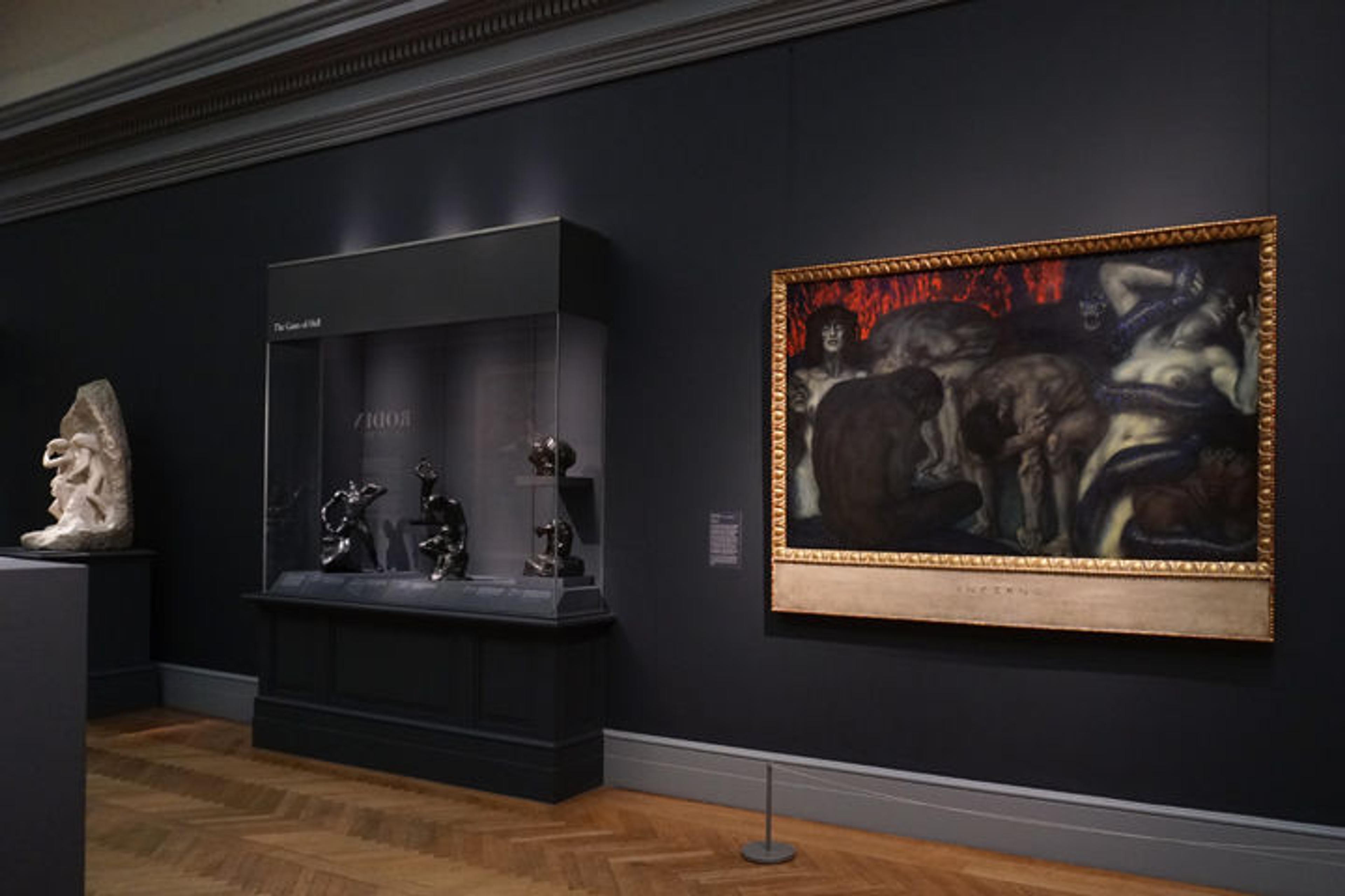 View of gallery 800 at The Met, where Franz von Stuck's 'Inferno' is installed to the right of a vitrine of Auguste Rodin's sculptures for 'The Gates of Hell'
