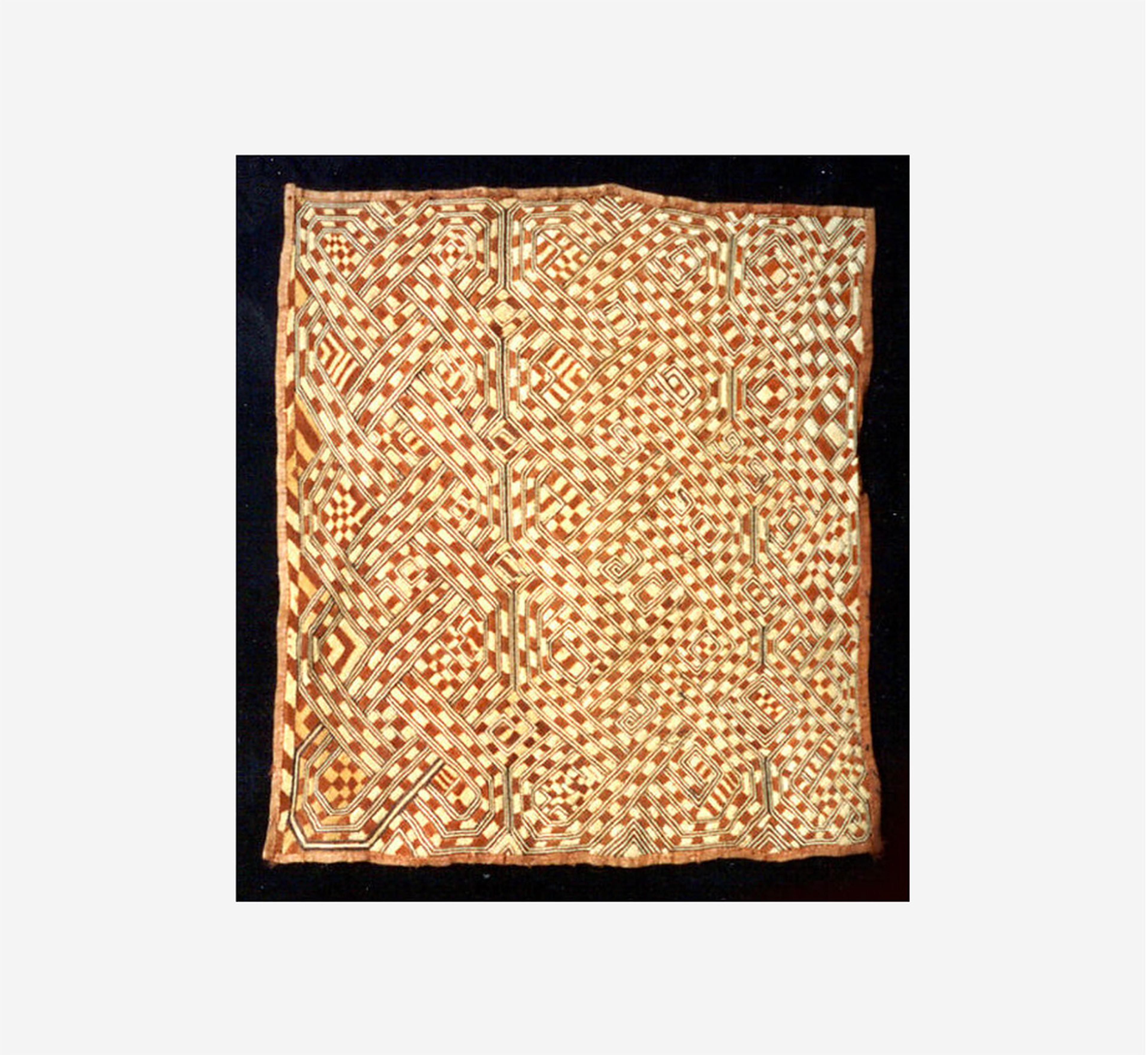 Woven textile with an intricate grid of interlocking geometric patterns in brown, cream, and reddish tones.