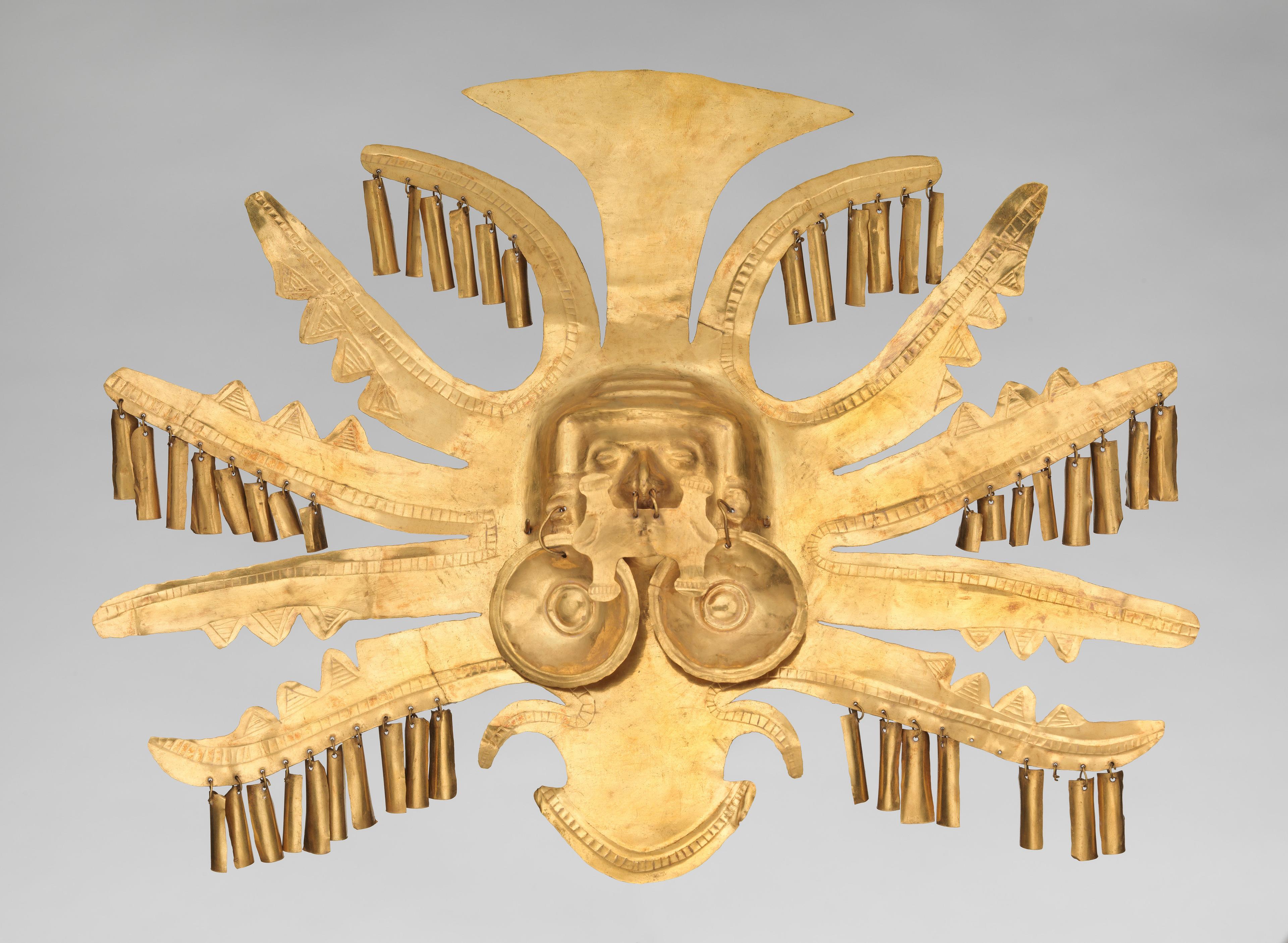 Five lateral rays project out from either side of this gold Calima headdress ornament, surrounding central crescent-shaped projections located both above and below a central face rendered in high relief.
