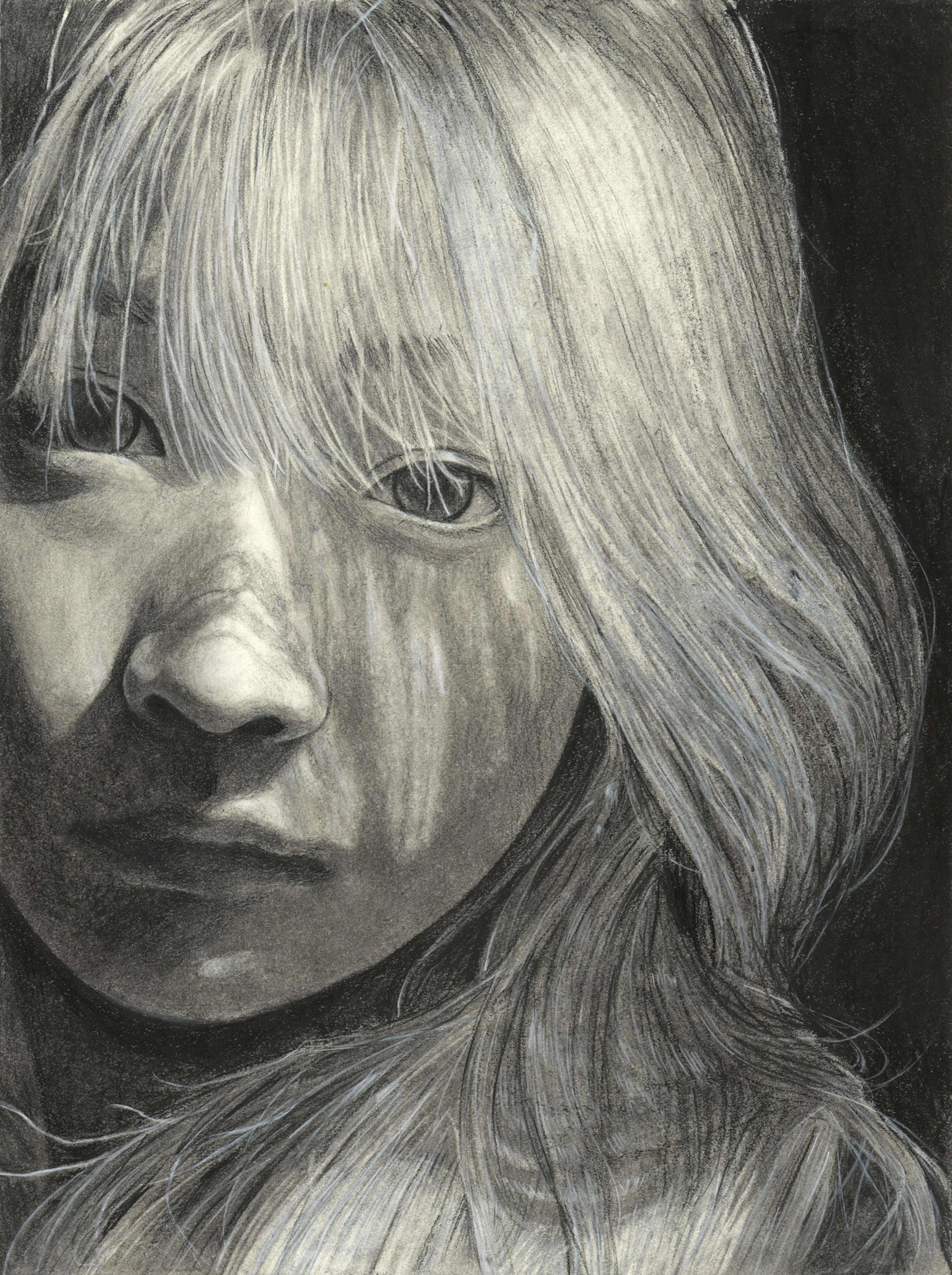 Charcoal on paper black and white photo- realistic self portrait of an adolescent Asian girl facing the viewer. Her long wavy hair falls beneath the shoulders, and is drawn in finely detailed strokes which cast elaborate patterns of light and shadow upon her nose and face.