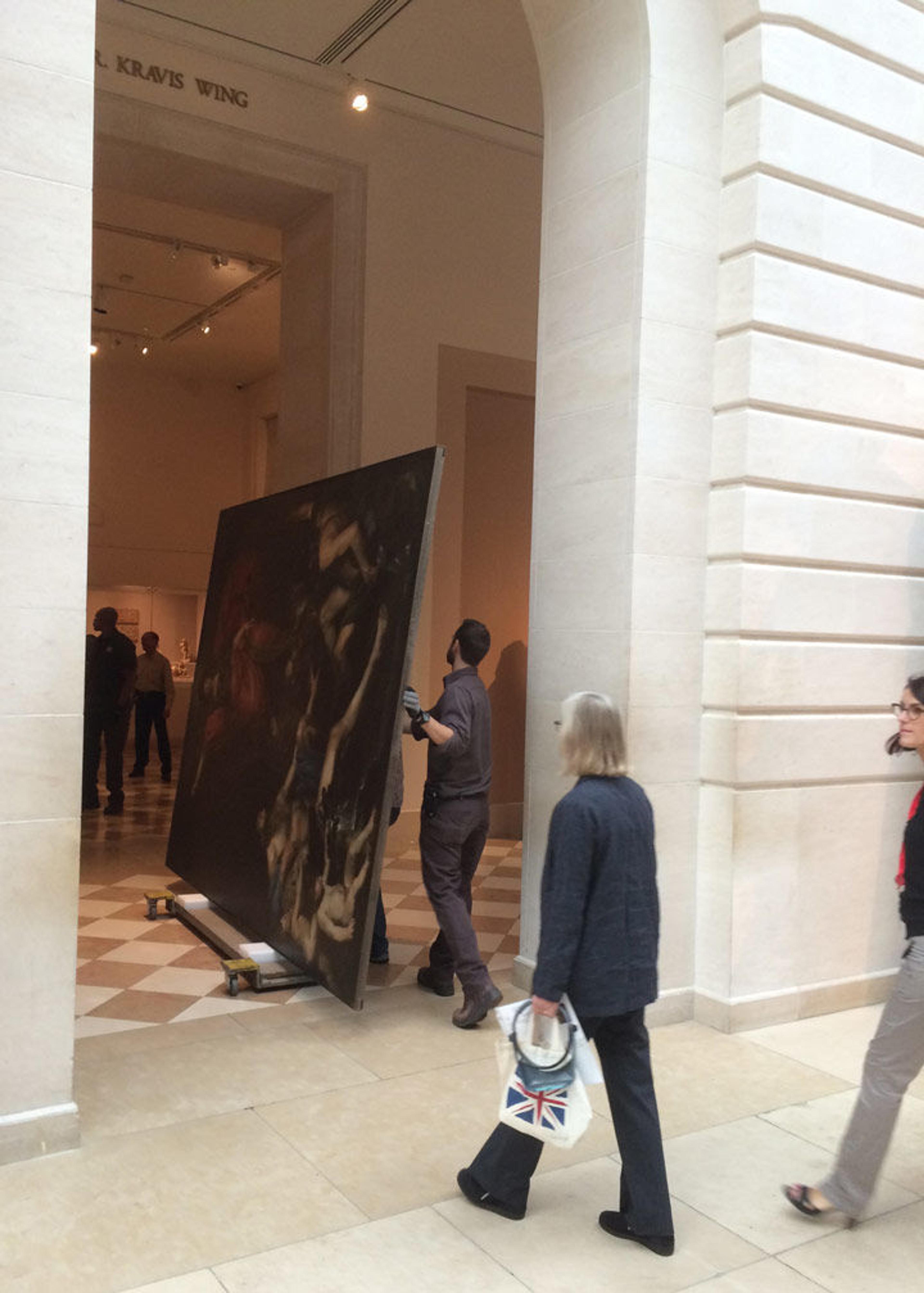 A group of technicians carefully move a Valentin de Boulogne painting through the Museum's European sculpture court