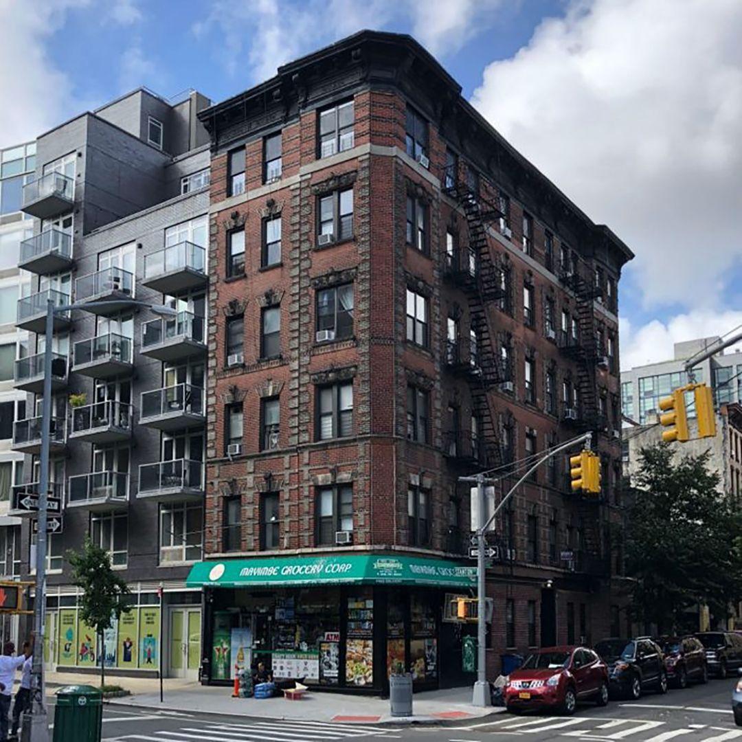 Contemporary photograph of a multi-story brick building on a city street corner.