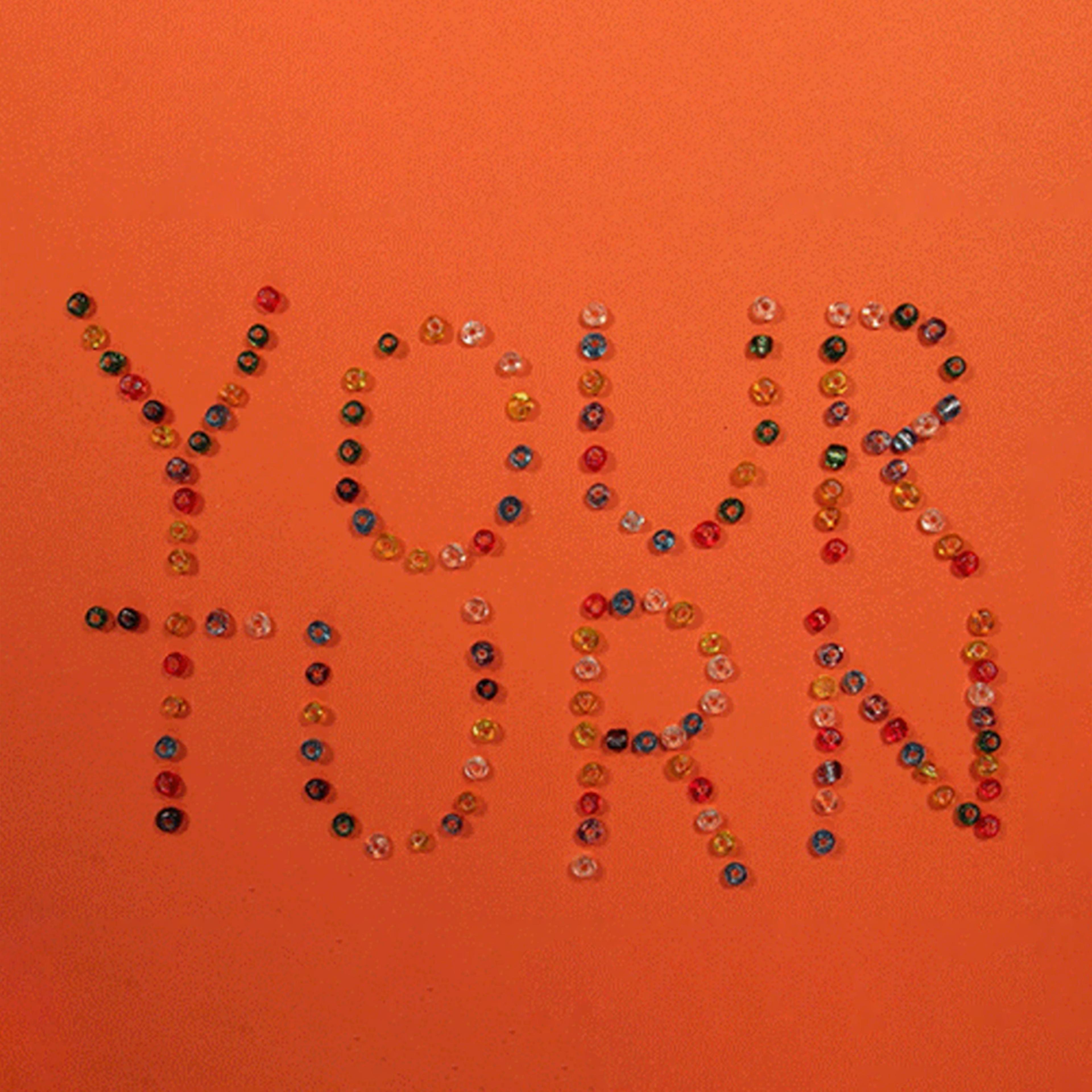 Beads spelling out "YOUR TURN" against an orange background.