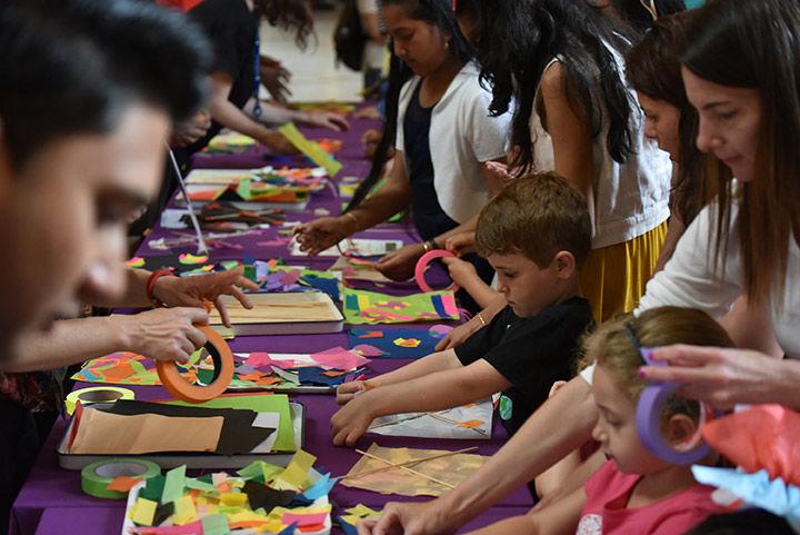 Kids and families working on art projects on a long, purple table.