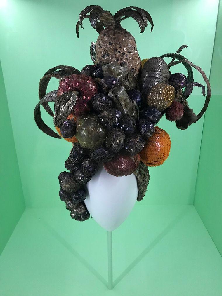 Installation view of Carmen Miranda's fruit turban, a sewn hat covered in fabric tropical fruit.