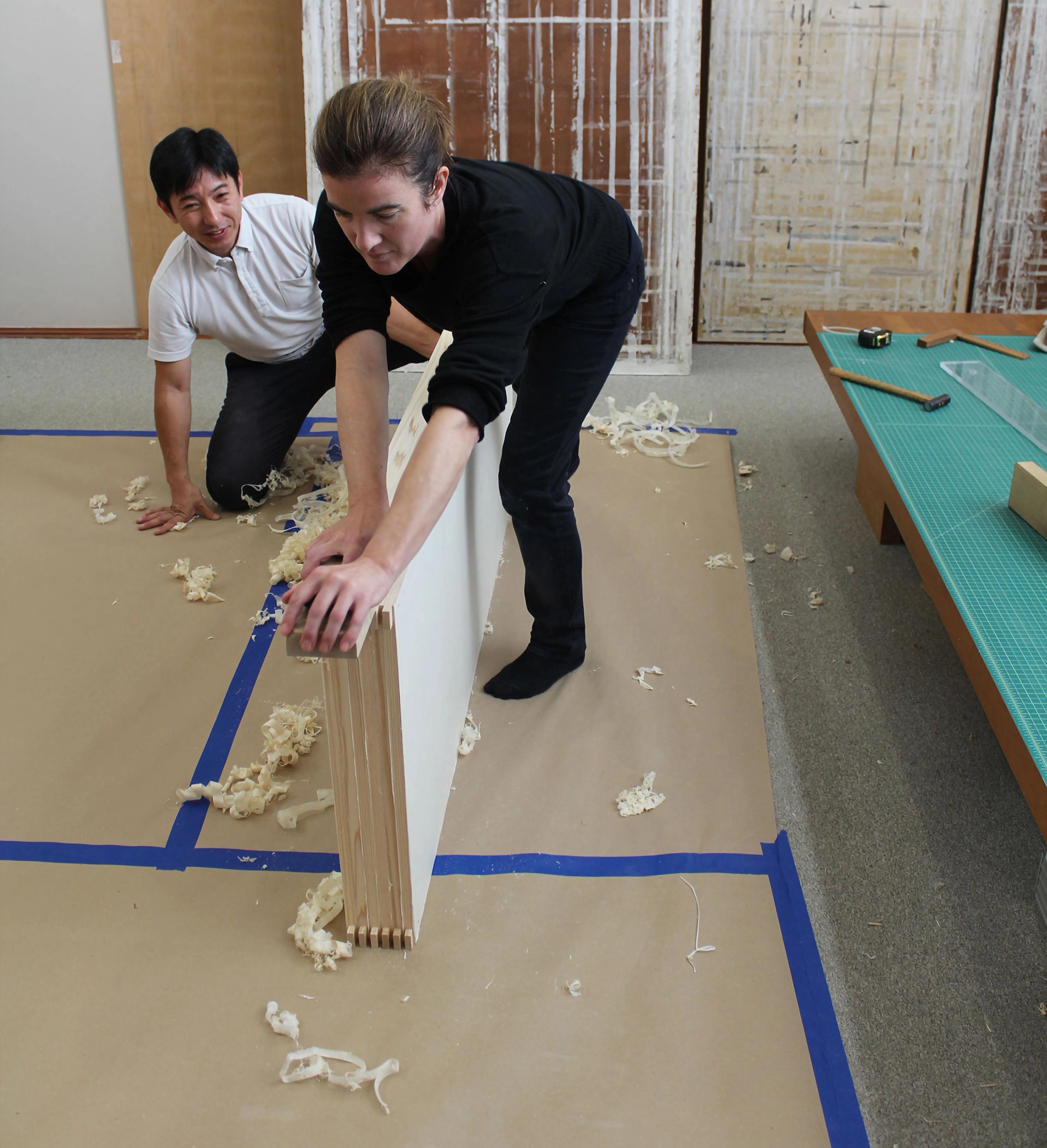 Woman in black planing a large piece of wood