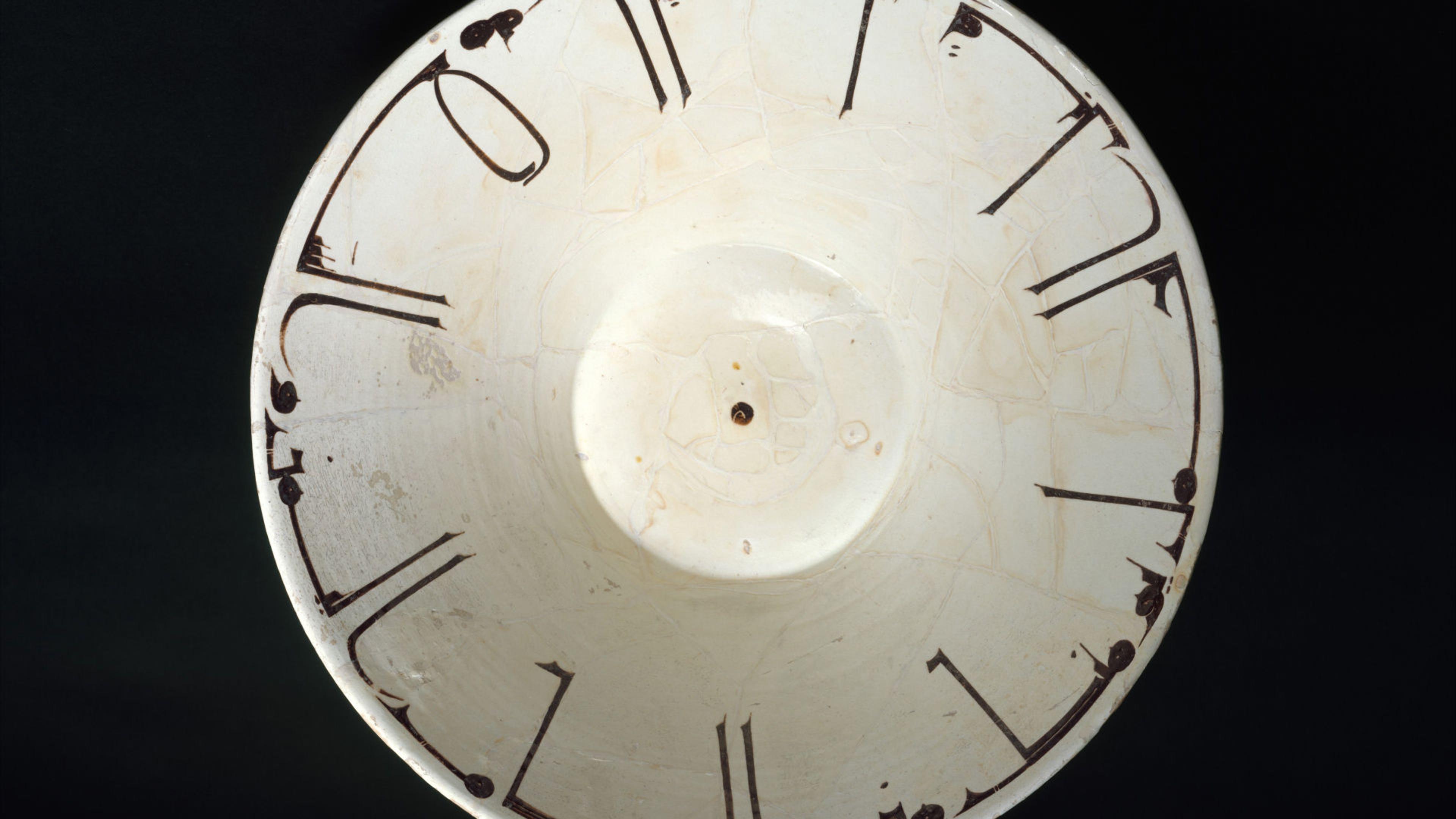 Off-white ceramic bowl with Arabic inscription front of a black background