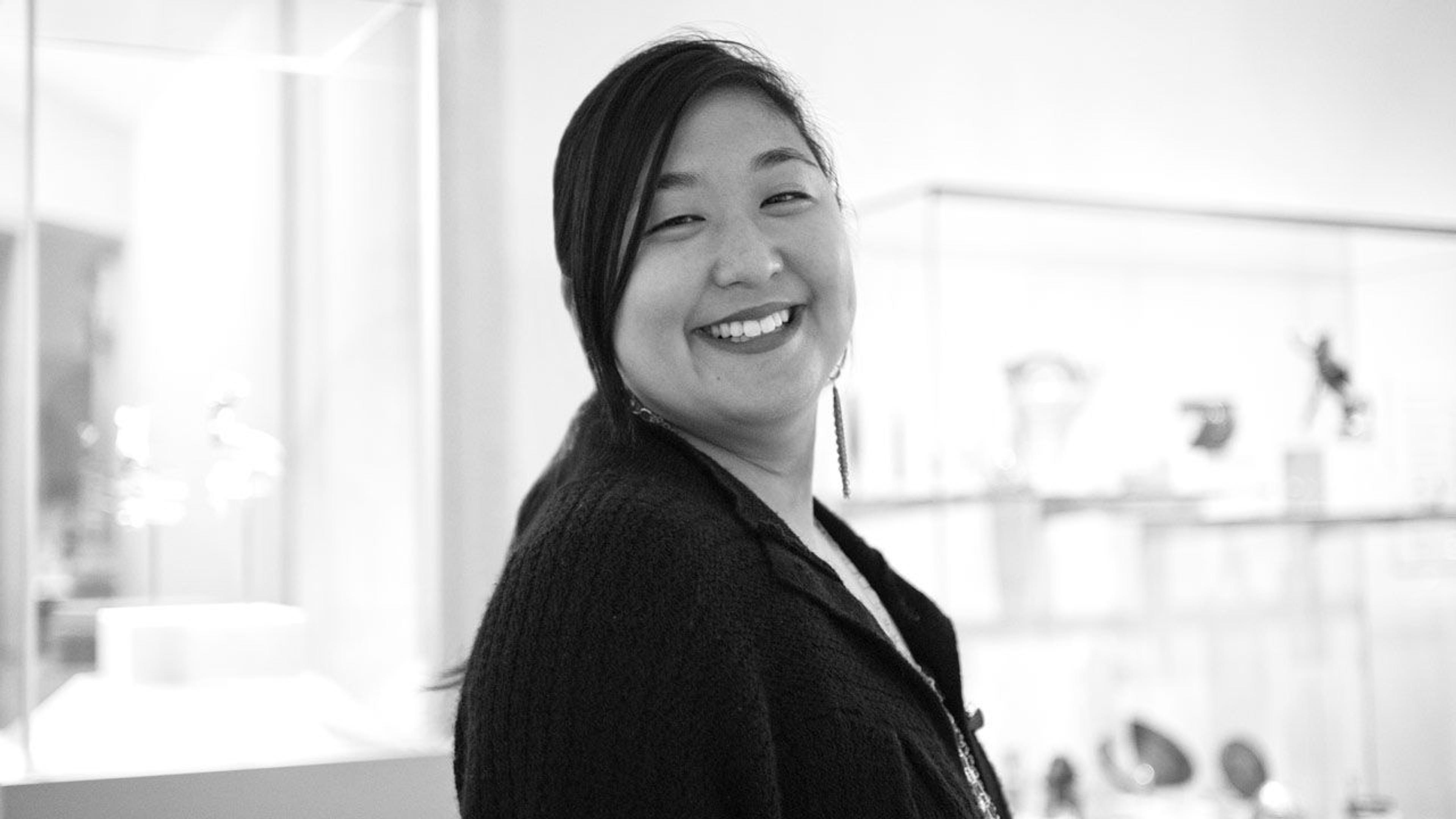 Black and white photograph of departmental administrator Debbie Kuo standing in a gallery at The Met