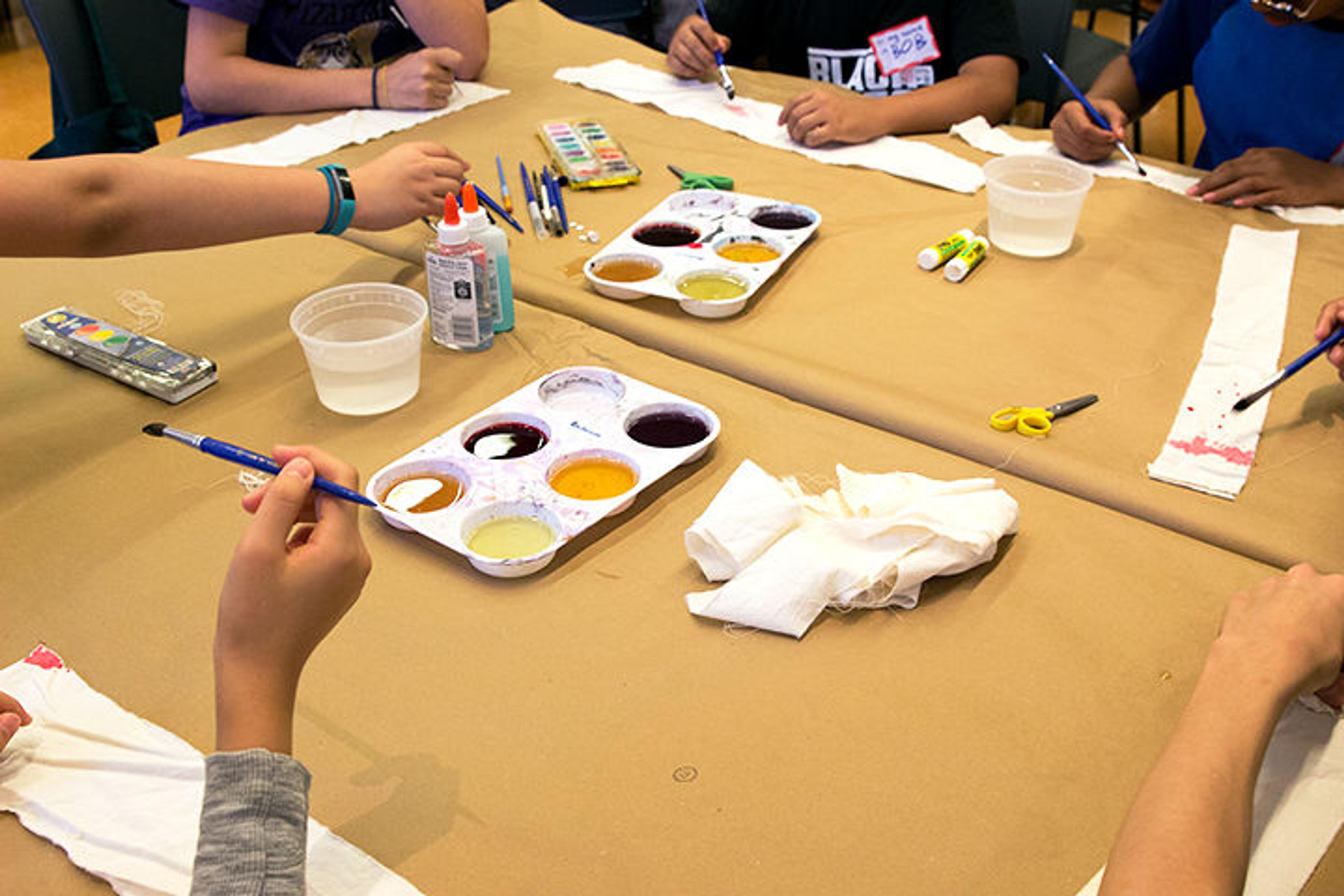 Kids and teens use brushes to paint the dye onto strips of muslin cloth.