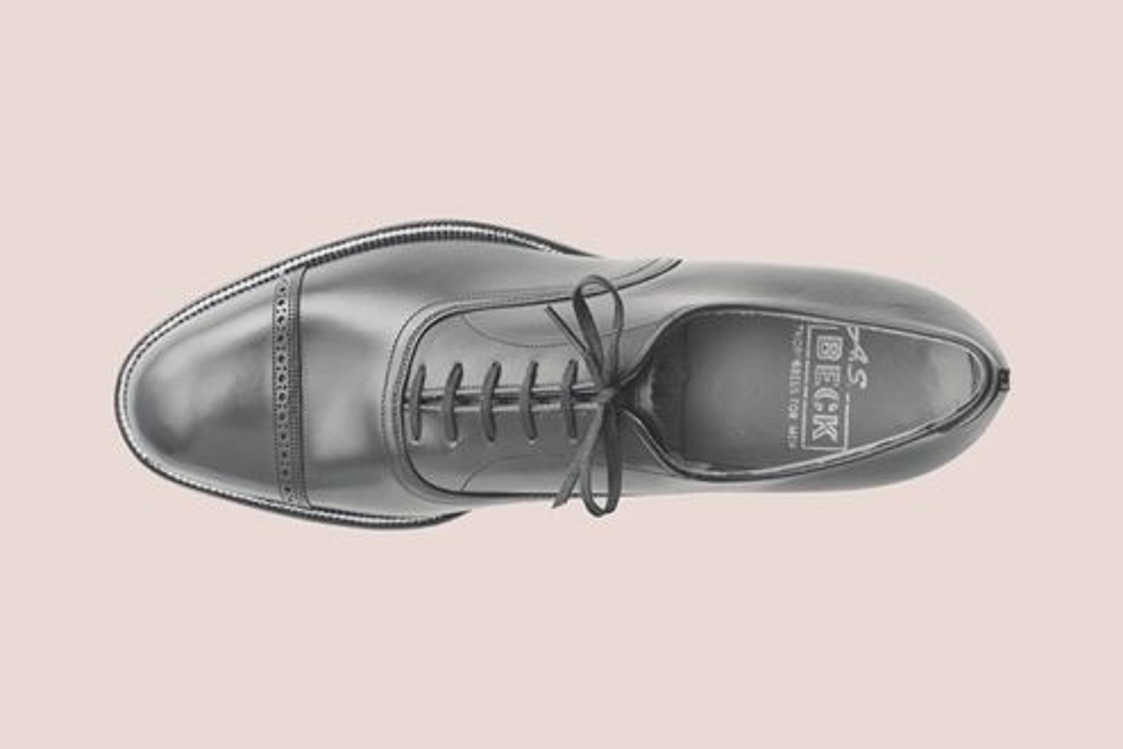 A photo of a leather shoe from aerial view. The shoe is oriented horizontally against a neutral backdrop.