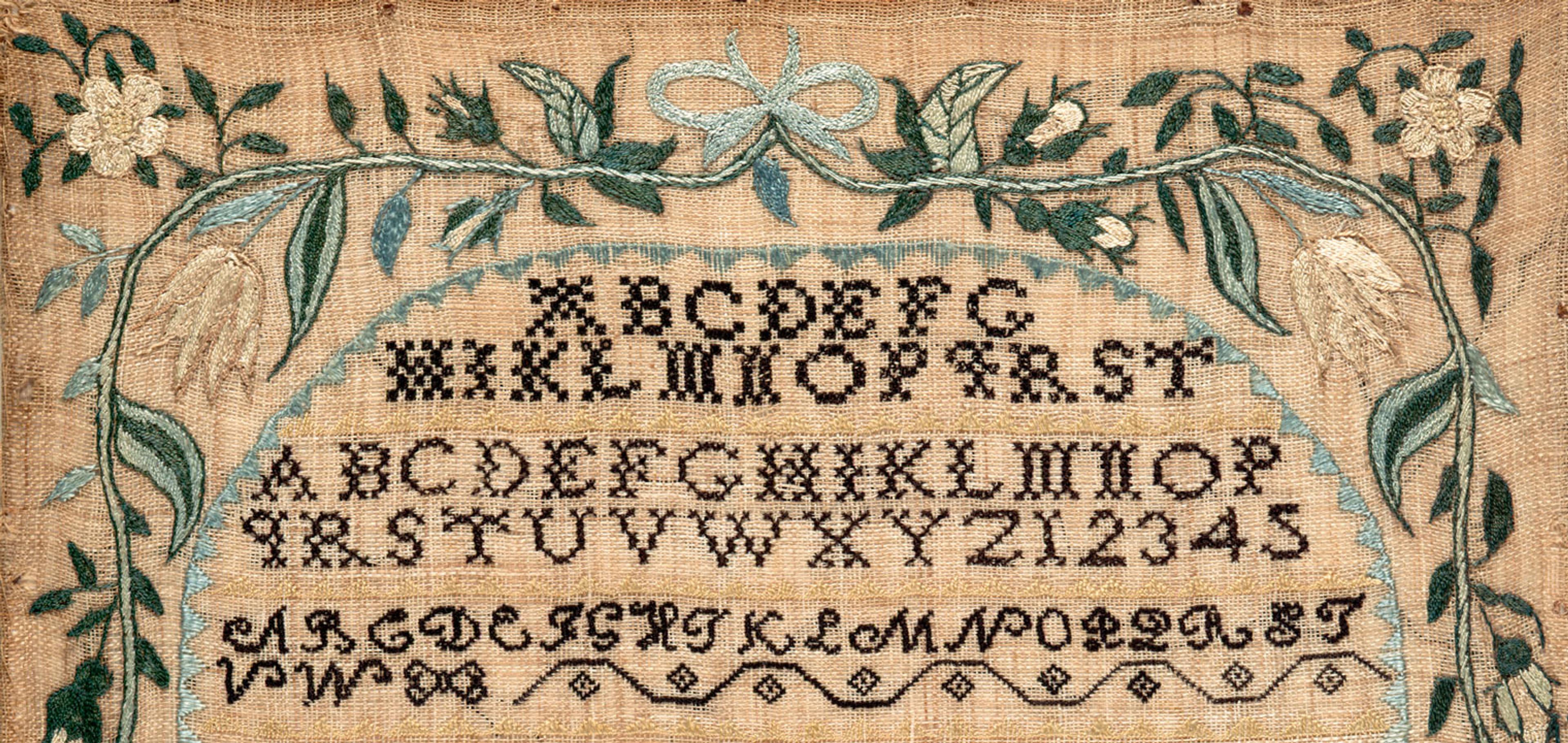 Image of a sampler by Lydia Pearson. The design features the alphabet and poetry embroidered in black thread onto tan linen cloth, surrounded by a border of blue, green, and cream-colored flowers, plants, and shapes.