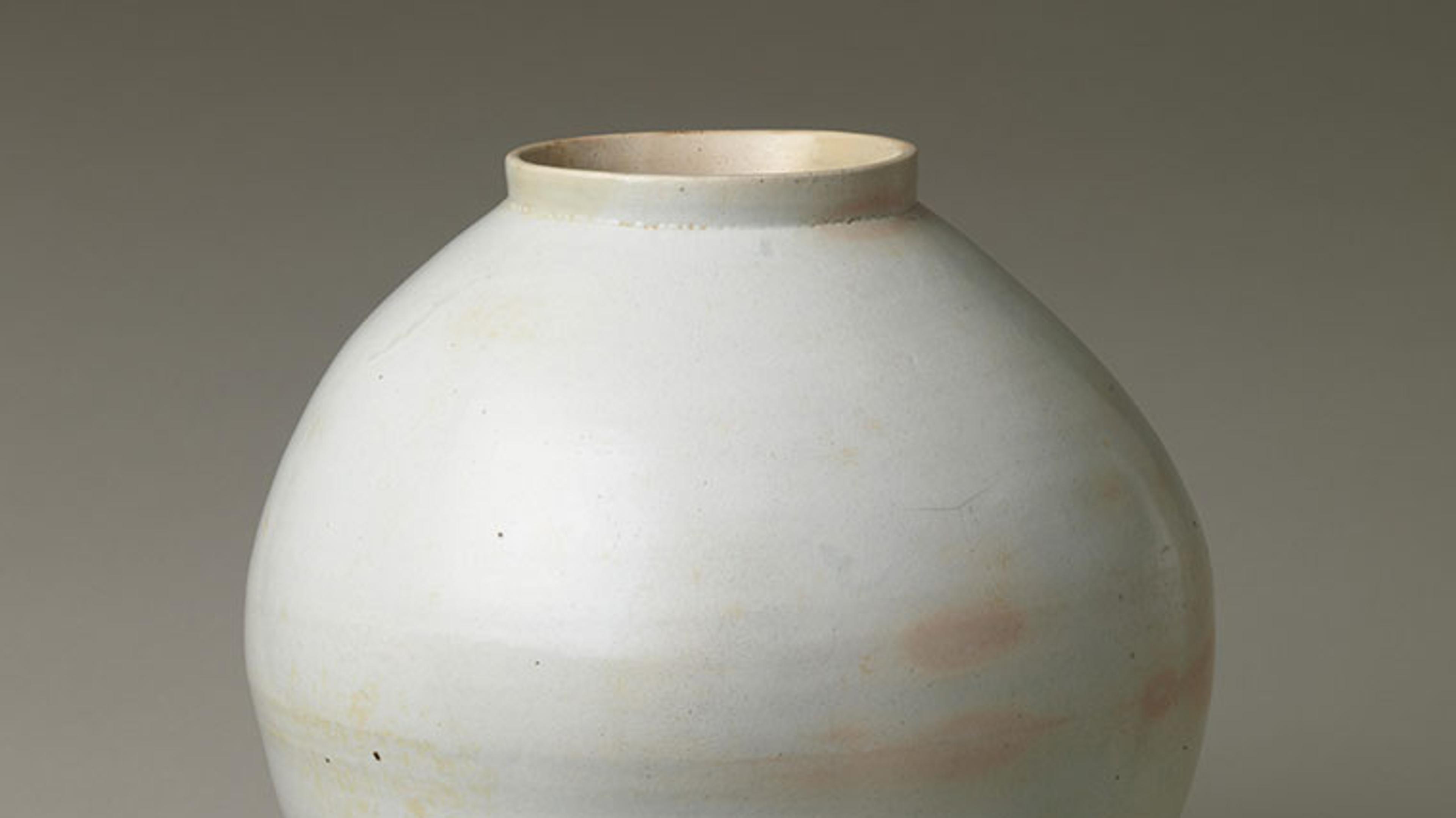A large, white jar with some peach colored spots around the center.