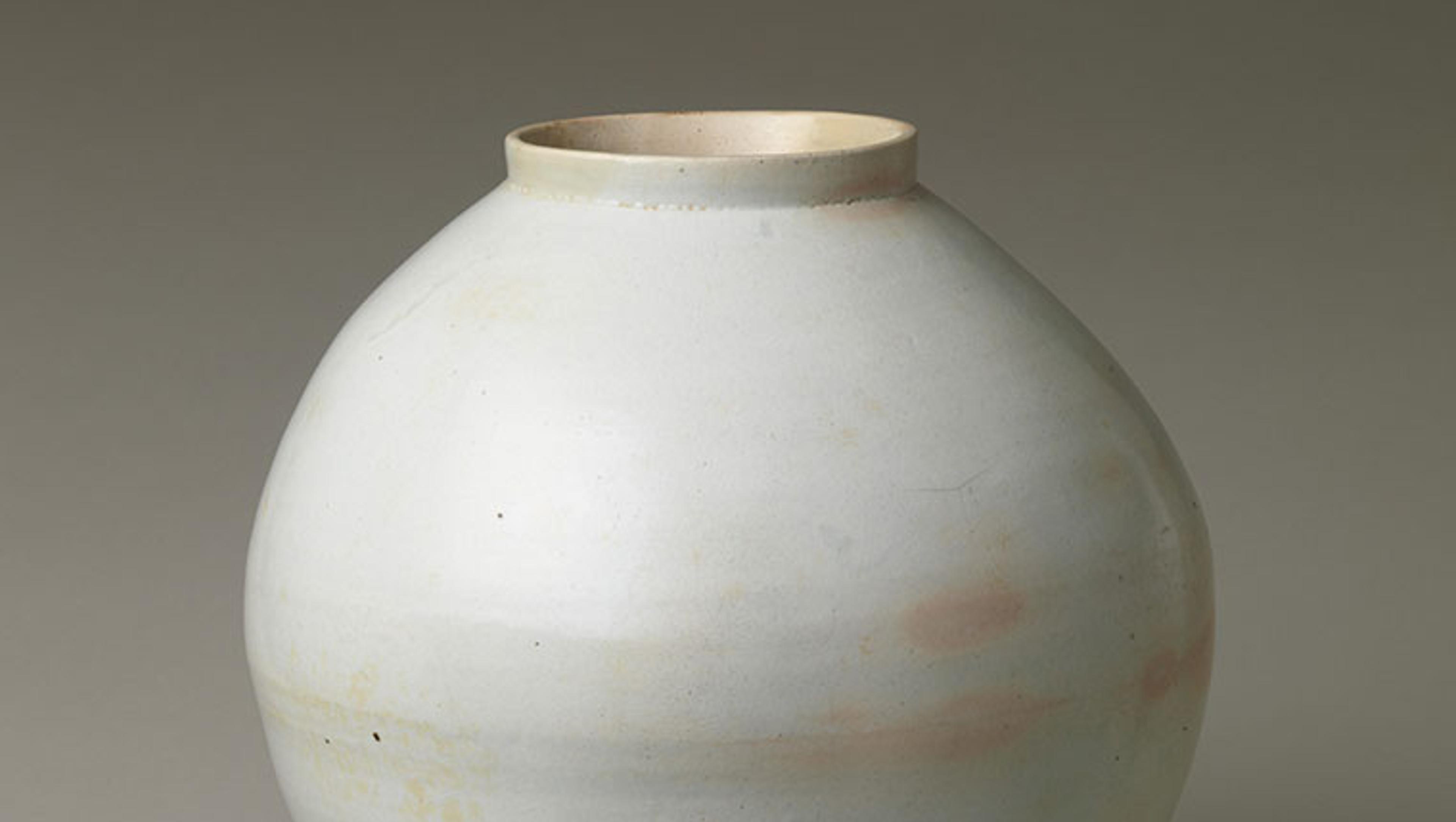 A large, white jar with some peach colored spots around the center.