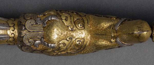 Detail of chiseled depth and chased texture in iron alloy of makara-head hilt