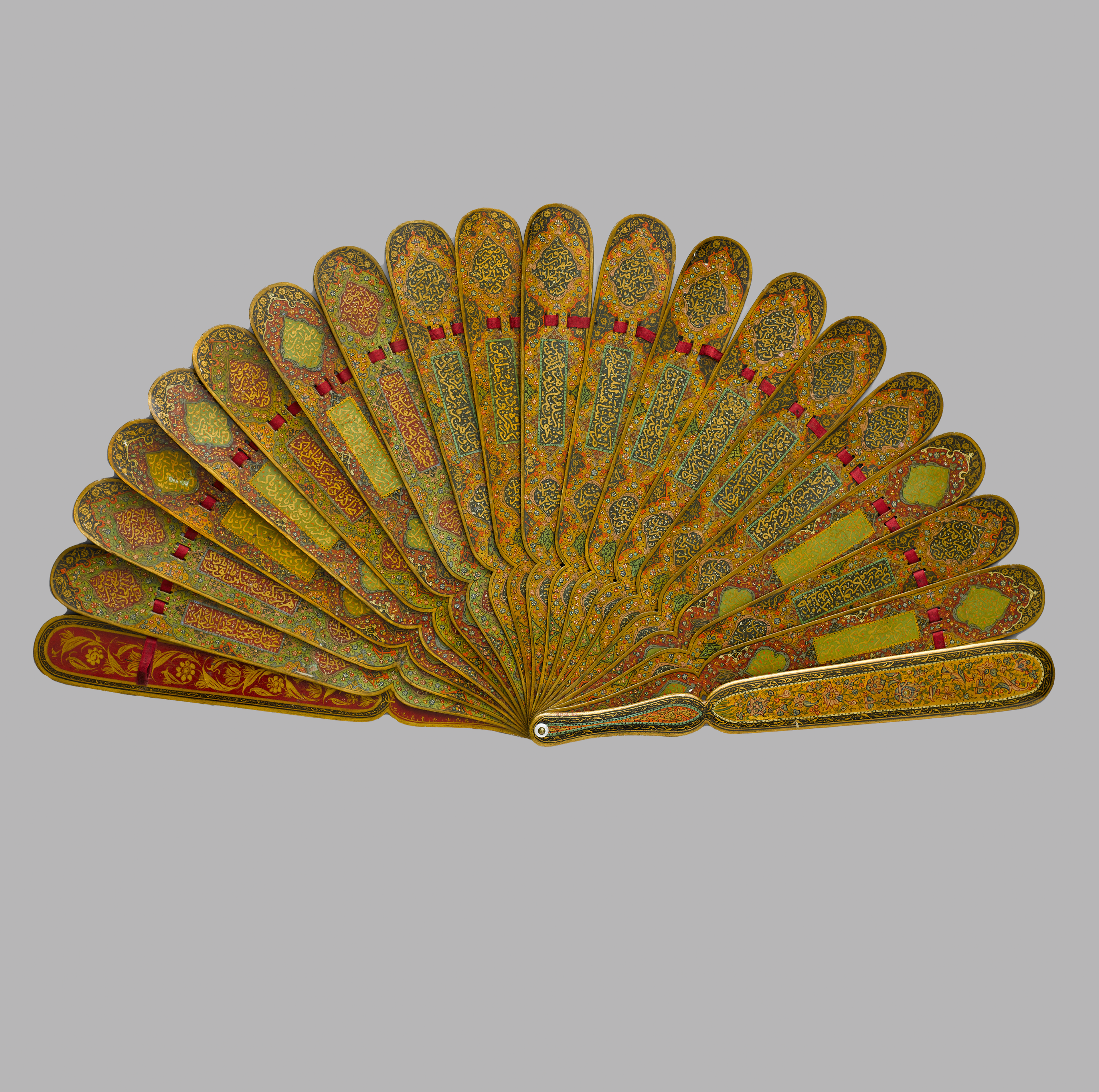 Ornate folding fan with golden patterns and red accents on each rib, intricately designed with floral motifs, displayed against a neutral background.