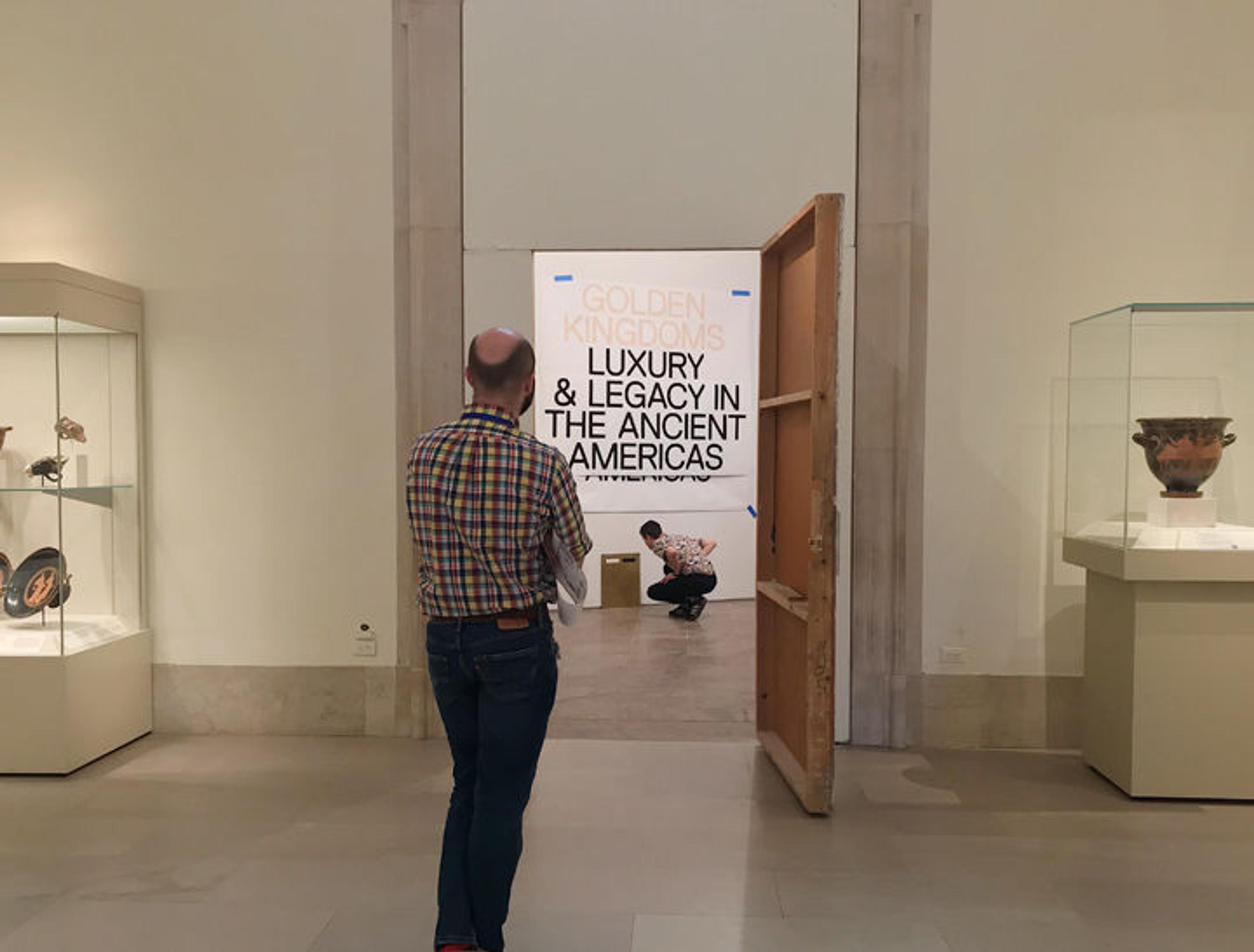 Two Met staff members see how an exhibition's title looks on a gallery wall