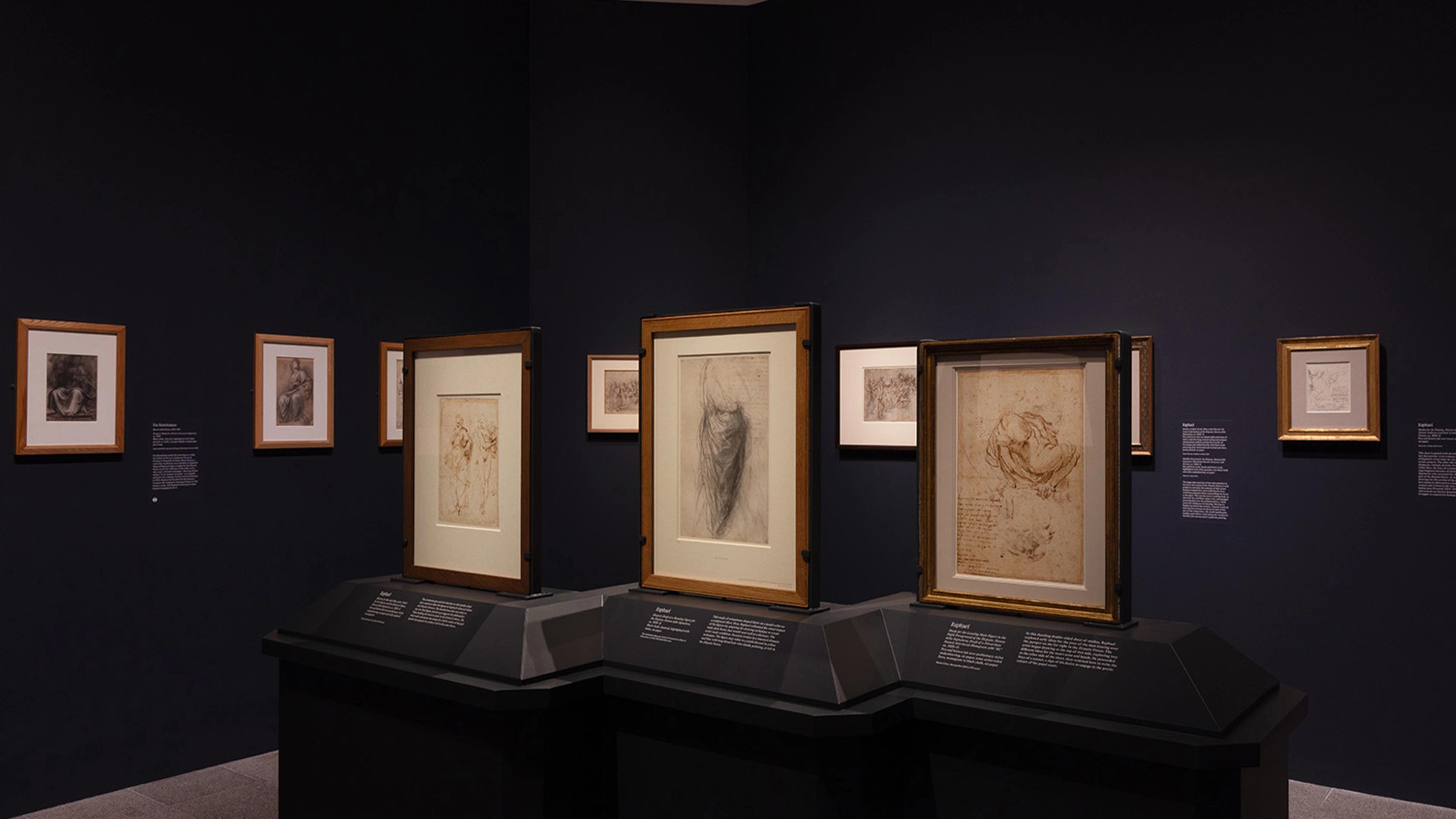 An art gallery displays framed sketches and drawings on dark walls.