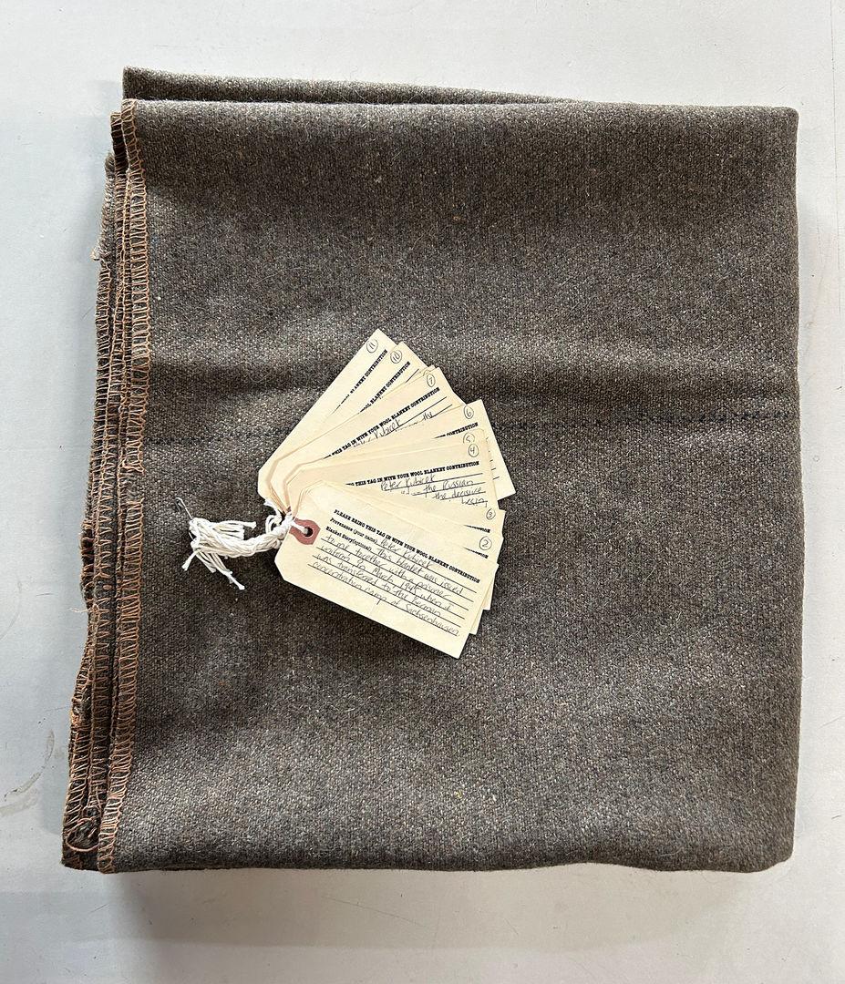 Simple, gray blanket. The tag identifies the owner as Peter Kubitschek, who elaborates that this blanket was issued to him at a Nazi concentration camp.