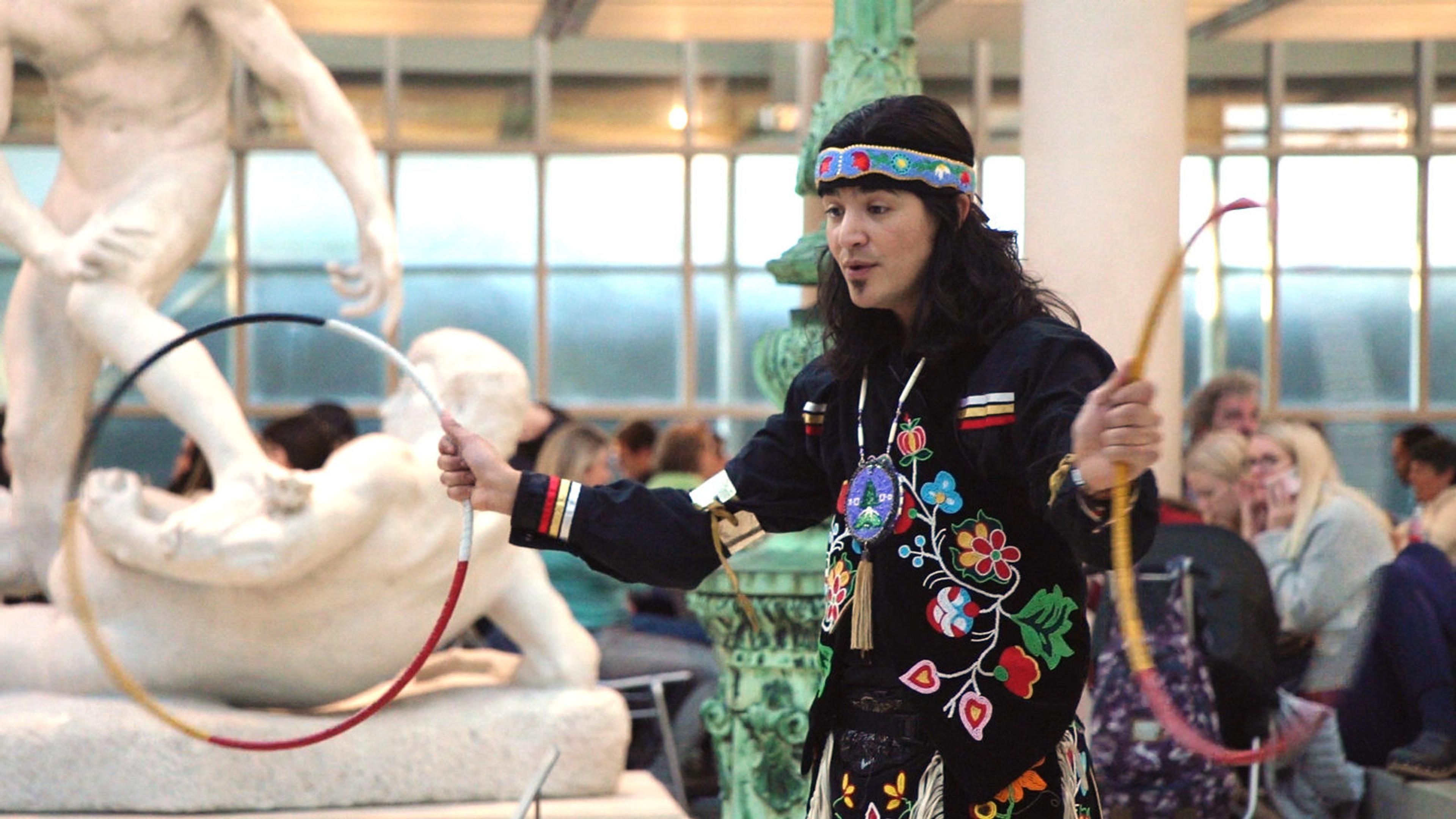 Artist Ty Defoe grips two colorful hoops in his hands and swings them through the air while performing at The Met.