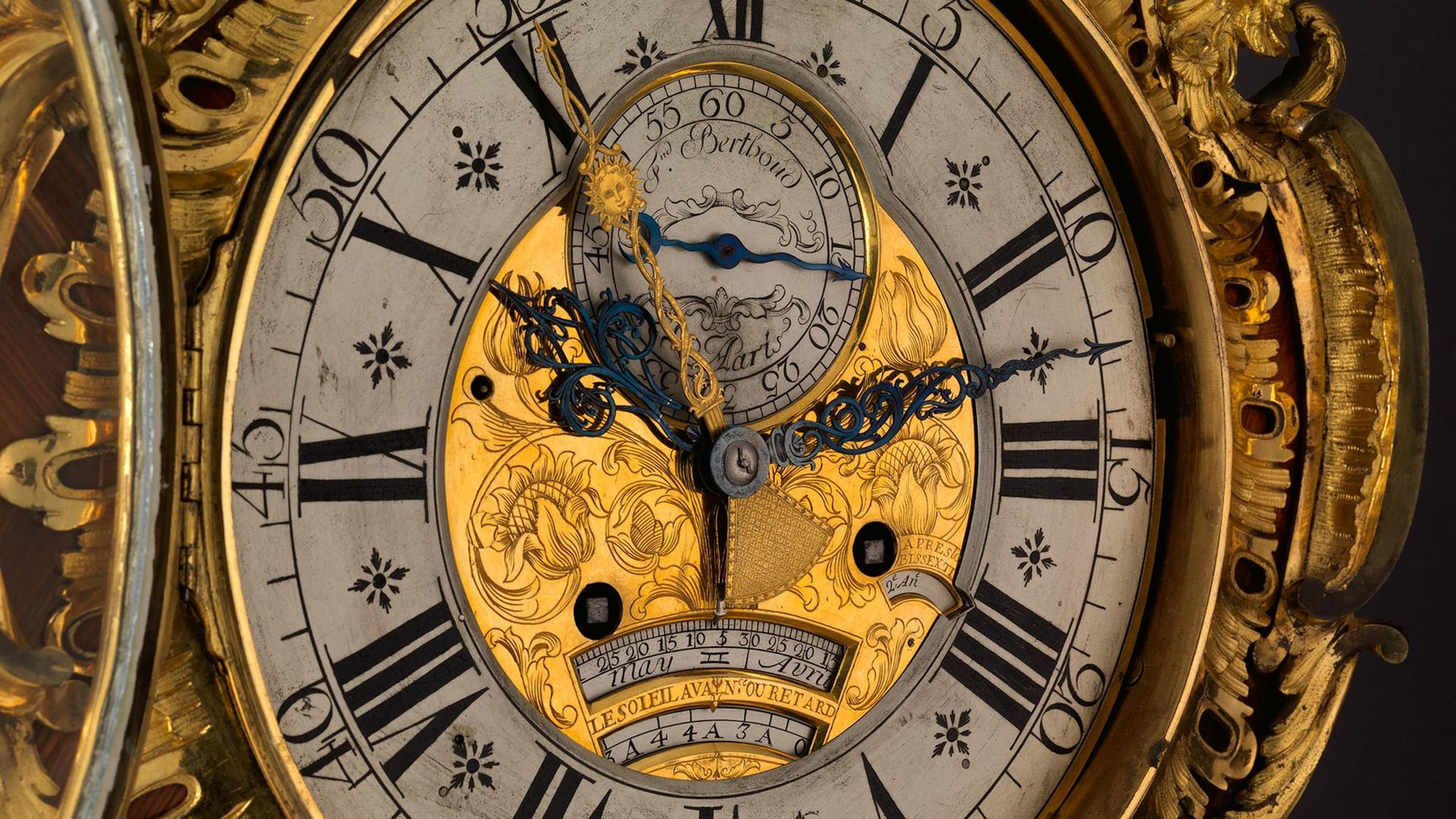 Close-up view of the face of an ornate clock embellished with gold