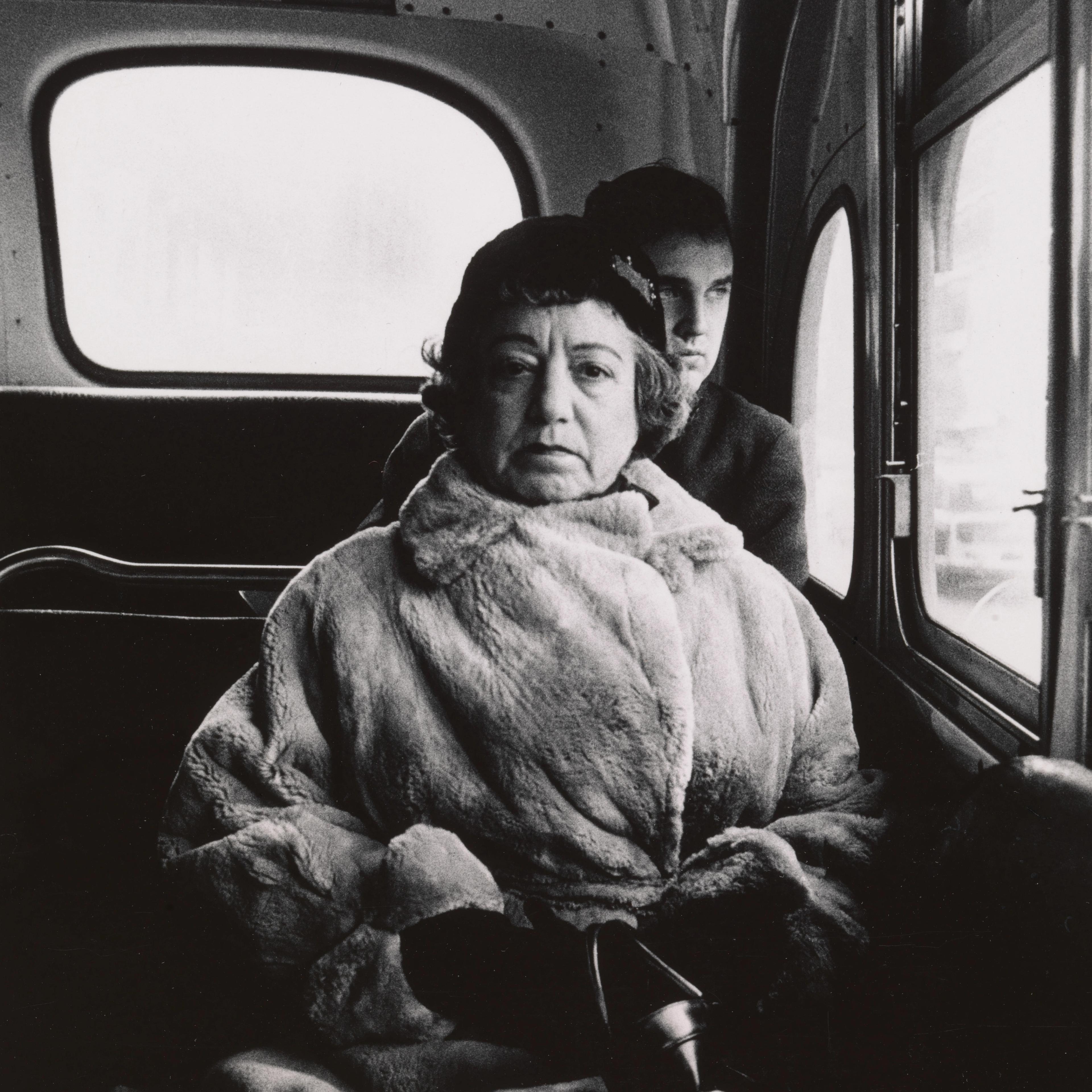 Black-and-white photograph of a woman on a bus.