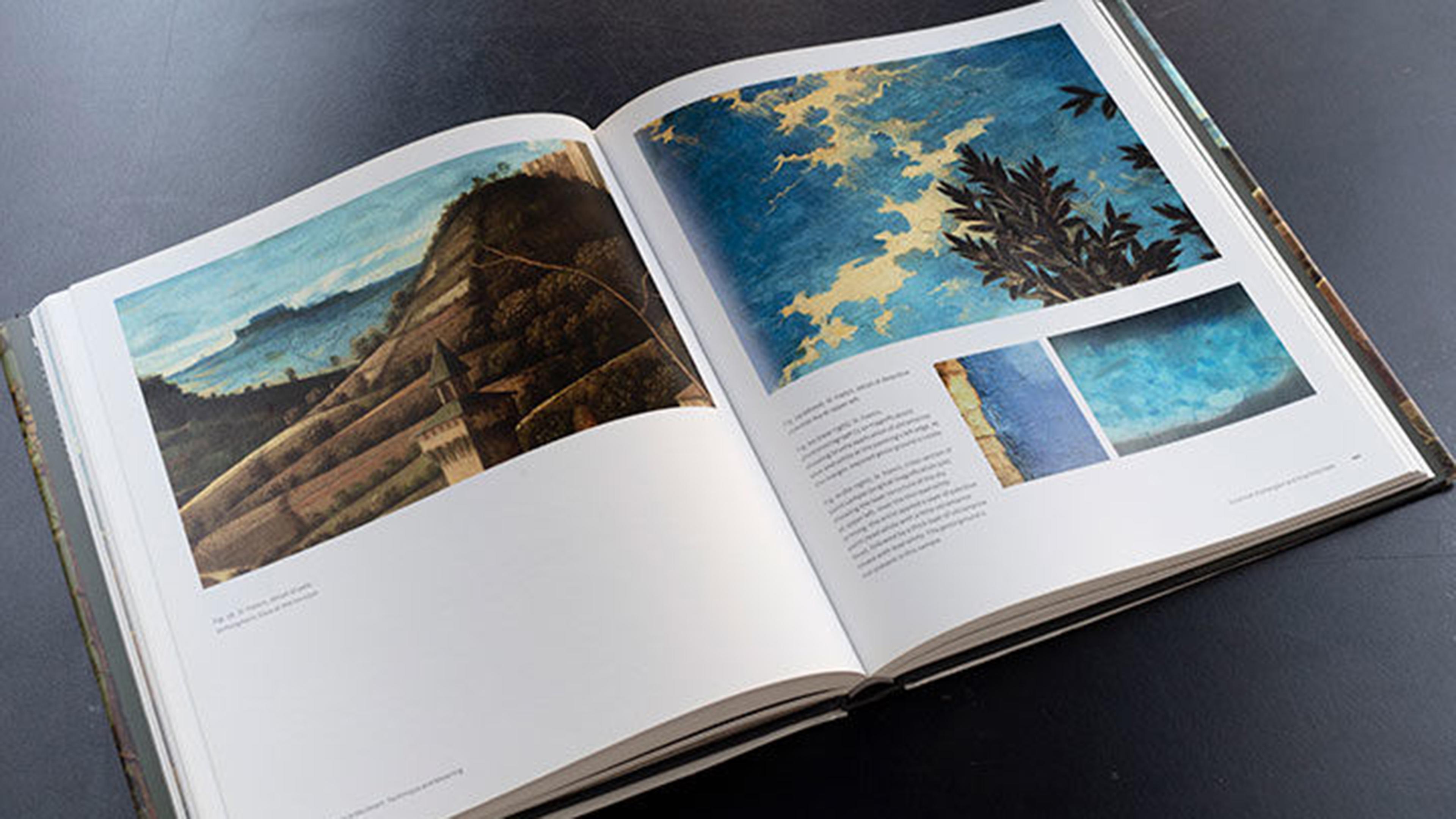 Opened book on a black table shows several details of Giovanni Bellini’s Saint Francis in the Desert, a painting from the Frick Collection.