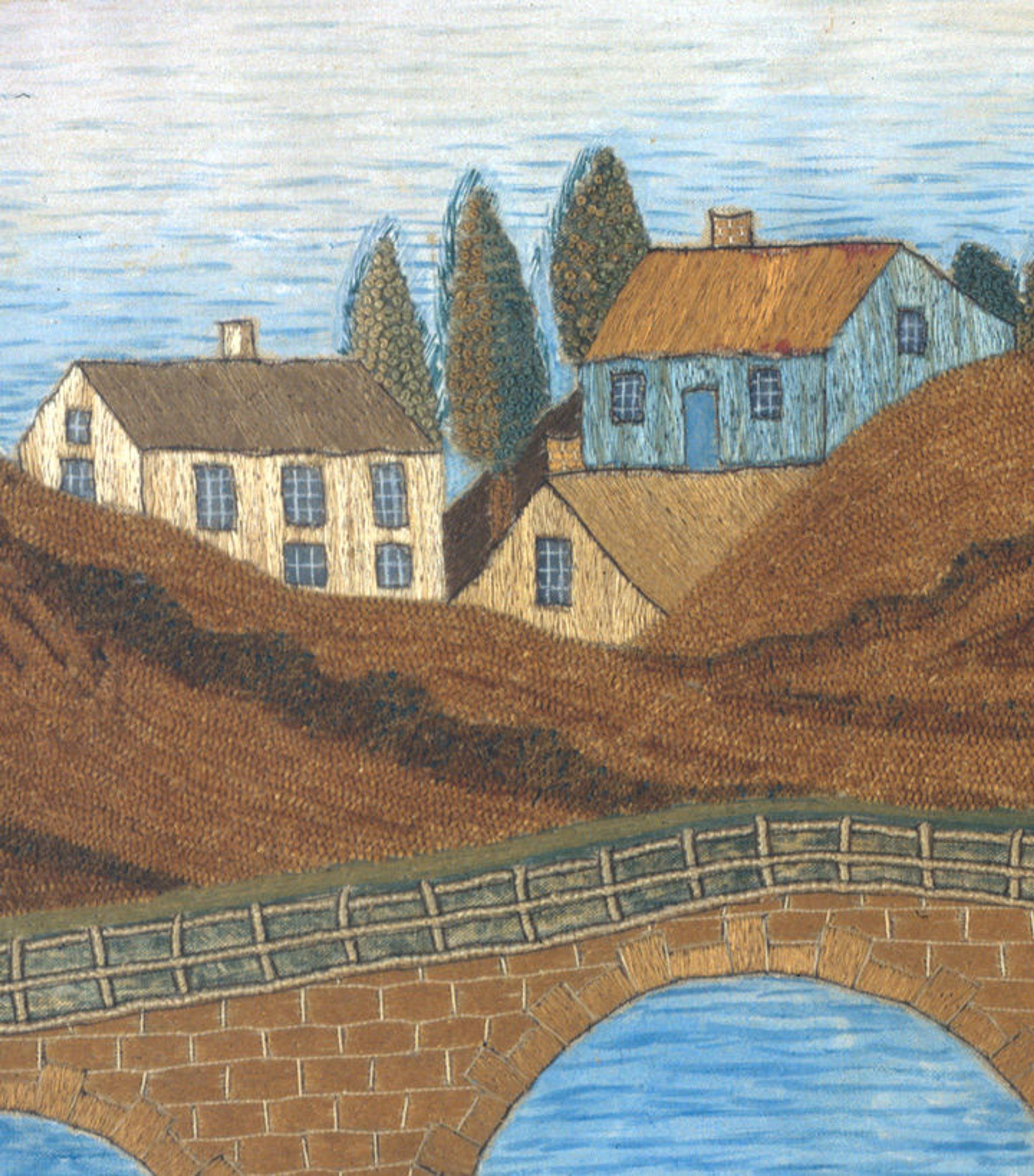 Detail of a needlework picture by Lucy Huntington shows distant blue and brown houses on a hillside, with a bridge and river below.
