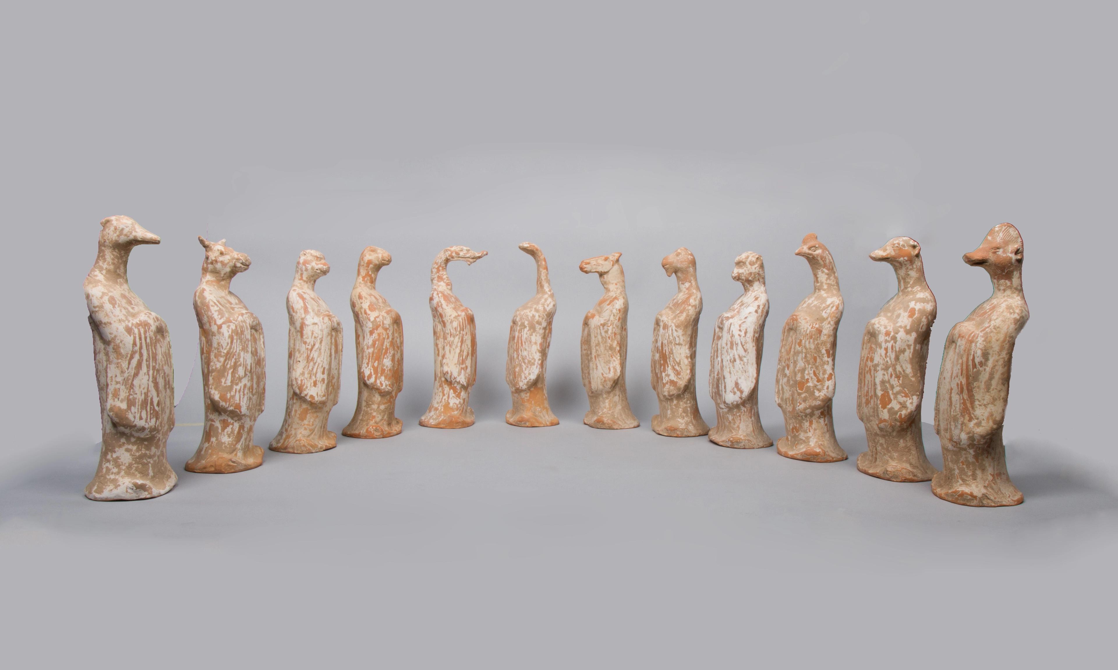 A group of twelve clay animal figurines arranged in a semicircle.
