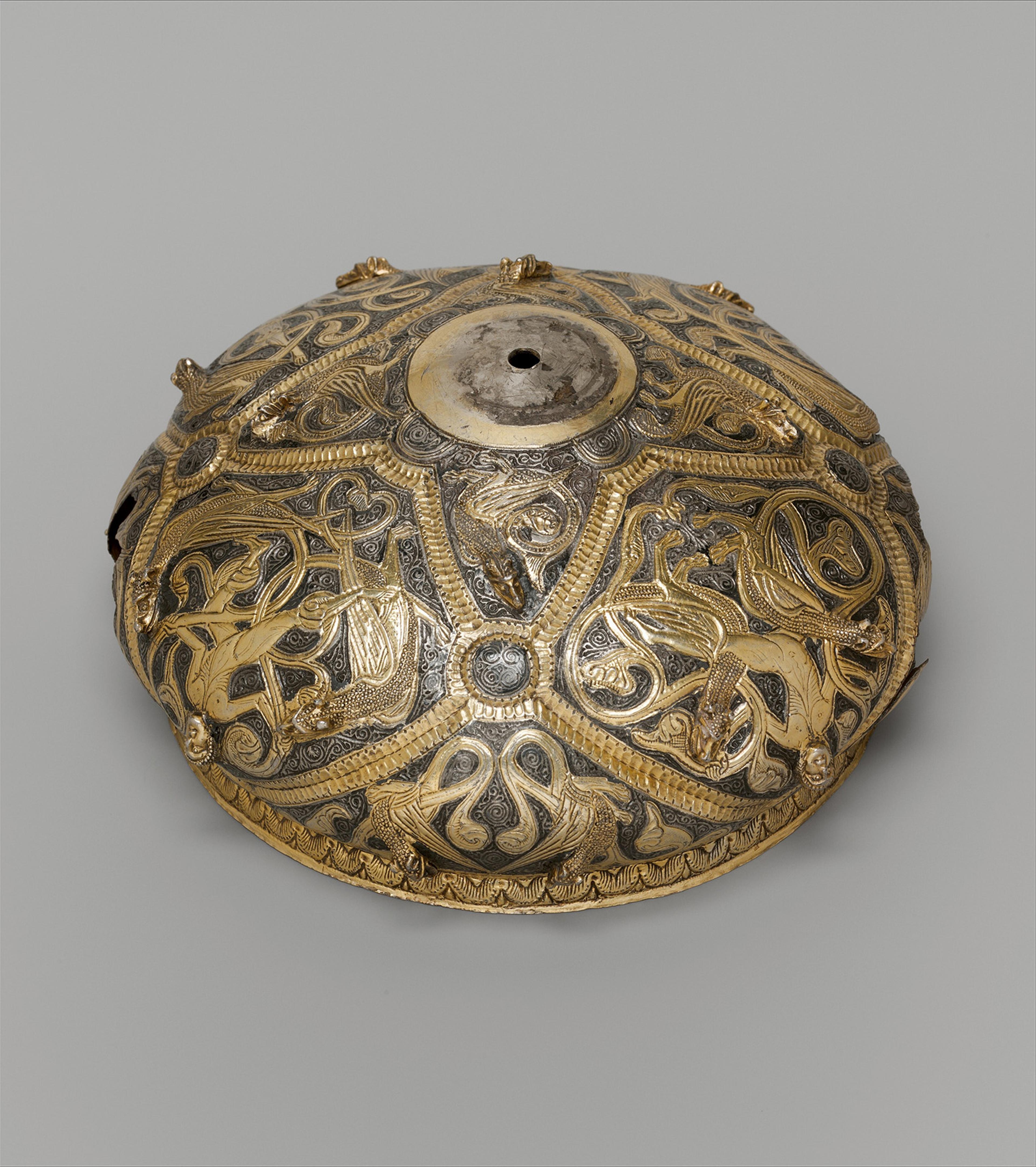 Ornate, round metal ornament with intricate gold and silver animal designs. 