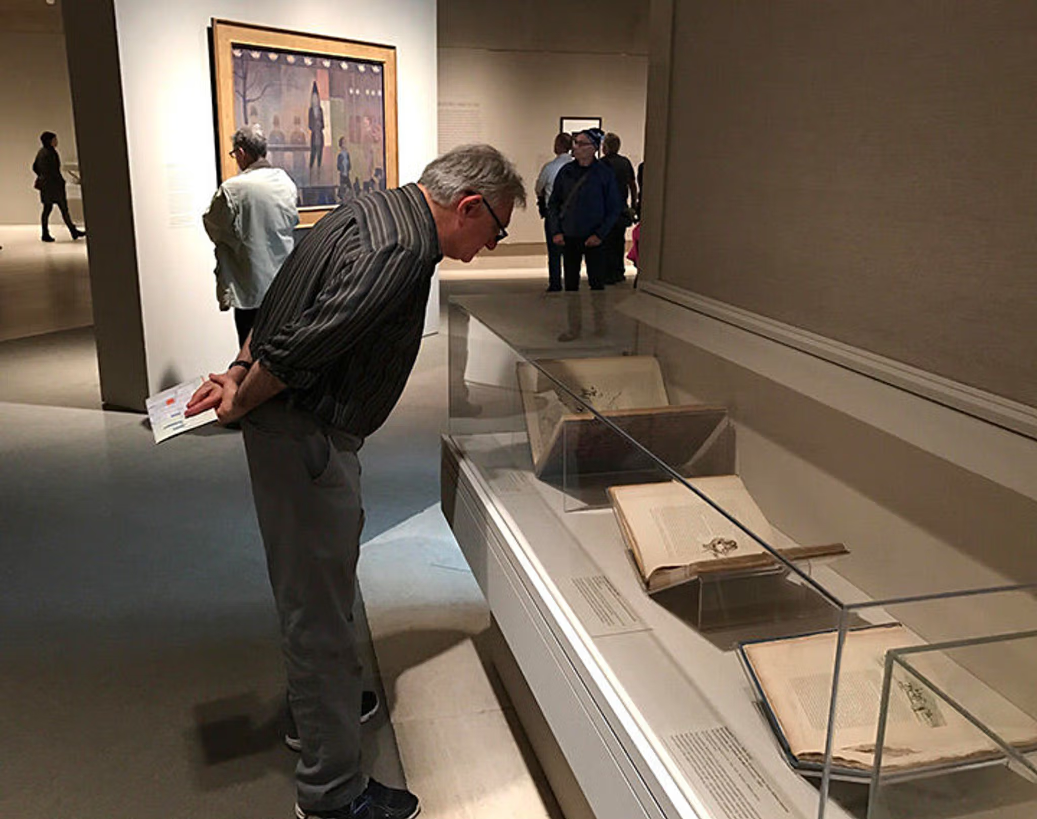 A visitor to the Seurat's Circus Sideshow exhibition peruses one of several vitrines displaying 19th-century books illustrating the French circus and parades, as well as color and aesthetic theory.