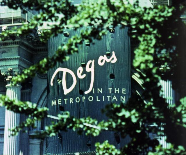 Exhibition banner for "Degas in the Metropolitan" hanging from The Met's facade, photographed through tree branches