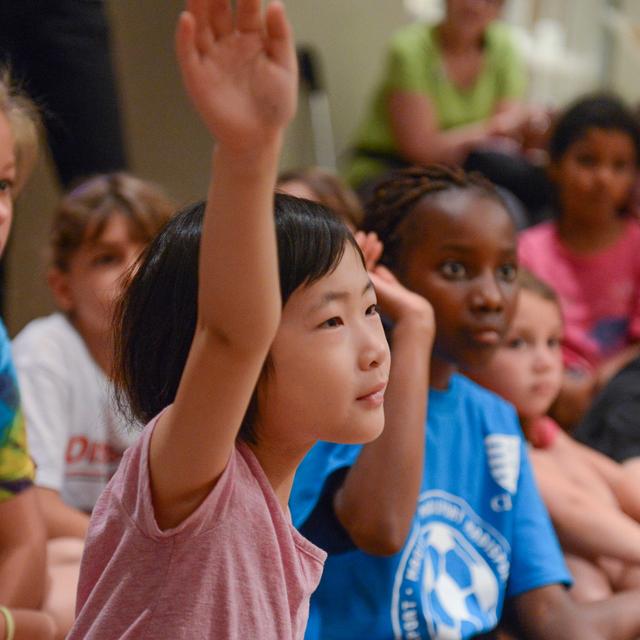 Young children raising their hands.