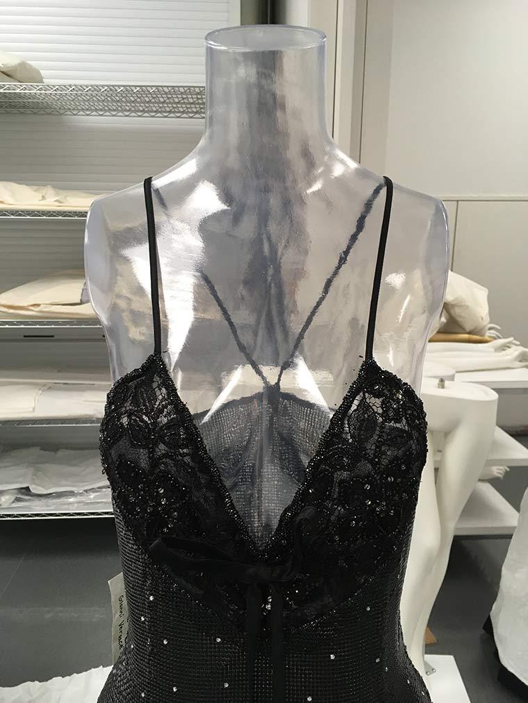 Black, mesh Versace dress with thin straps on a clear mannequin torso without arms.