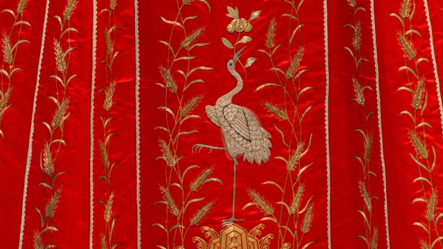 A traditional black robe features intricate gold embroidery with circular dragon motifs.