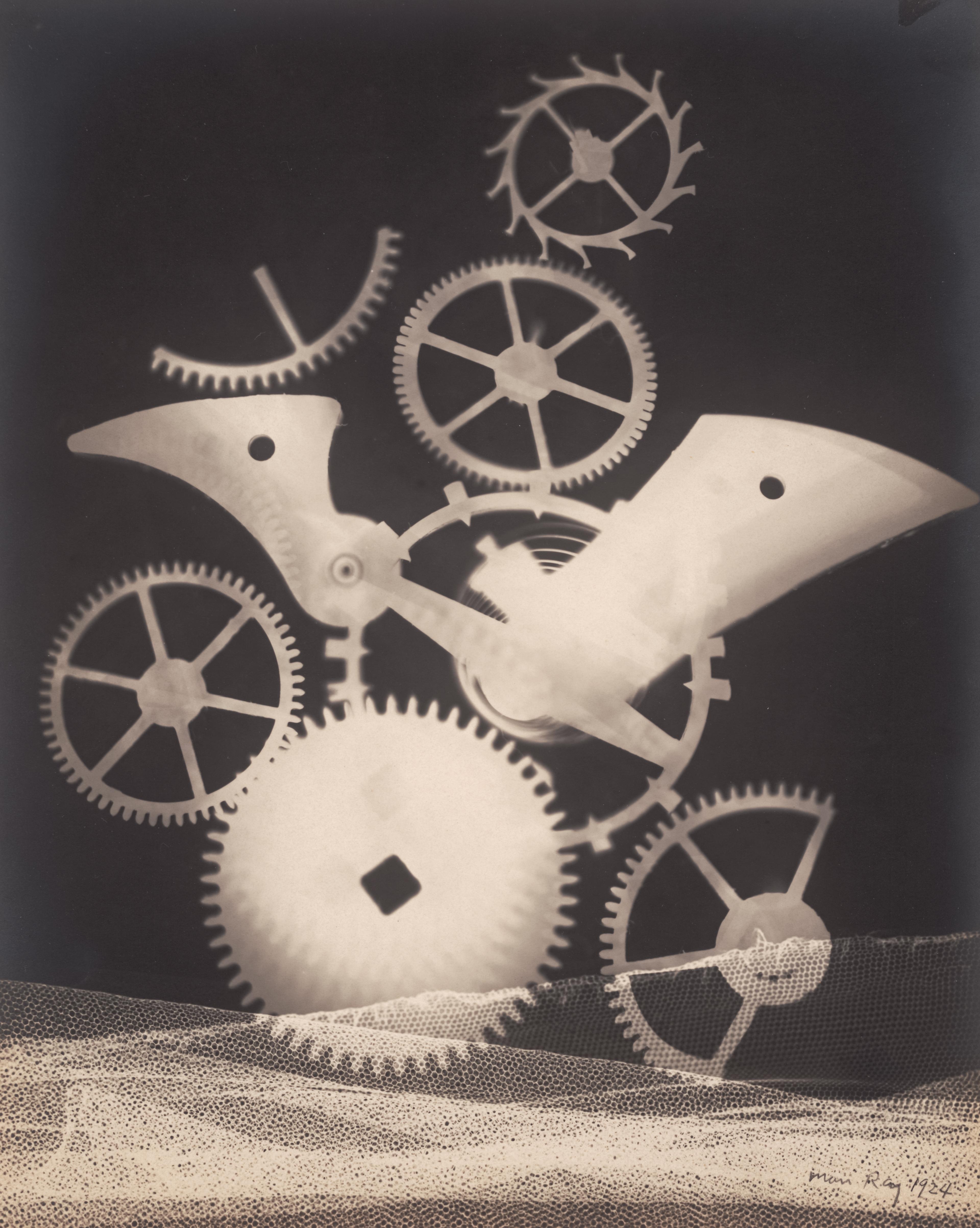 Rayograph of multiple overlapping gears with a strip of mesh at the bottom.