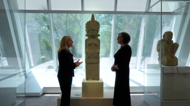 Joanne Pillsbury and Laura Filloy Nadal standing in front of a female sculpture in the Ancient Americas galleries of the Michael C. Rockefeller Wing
