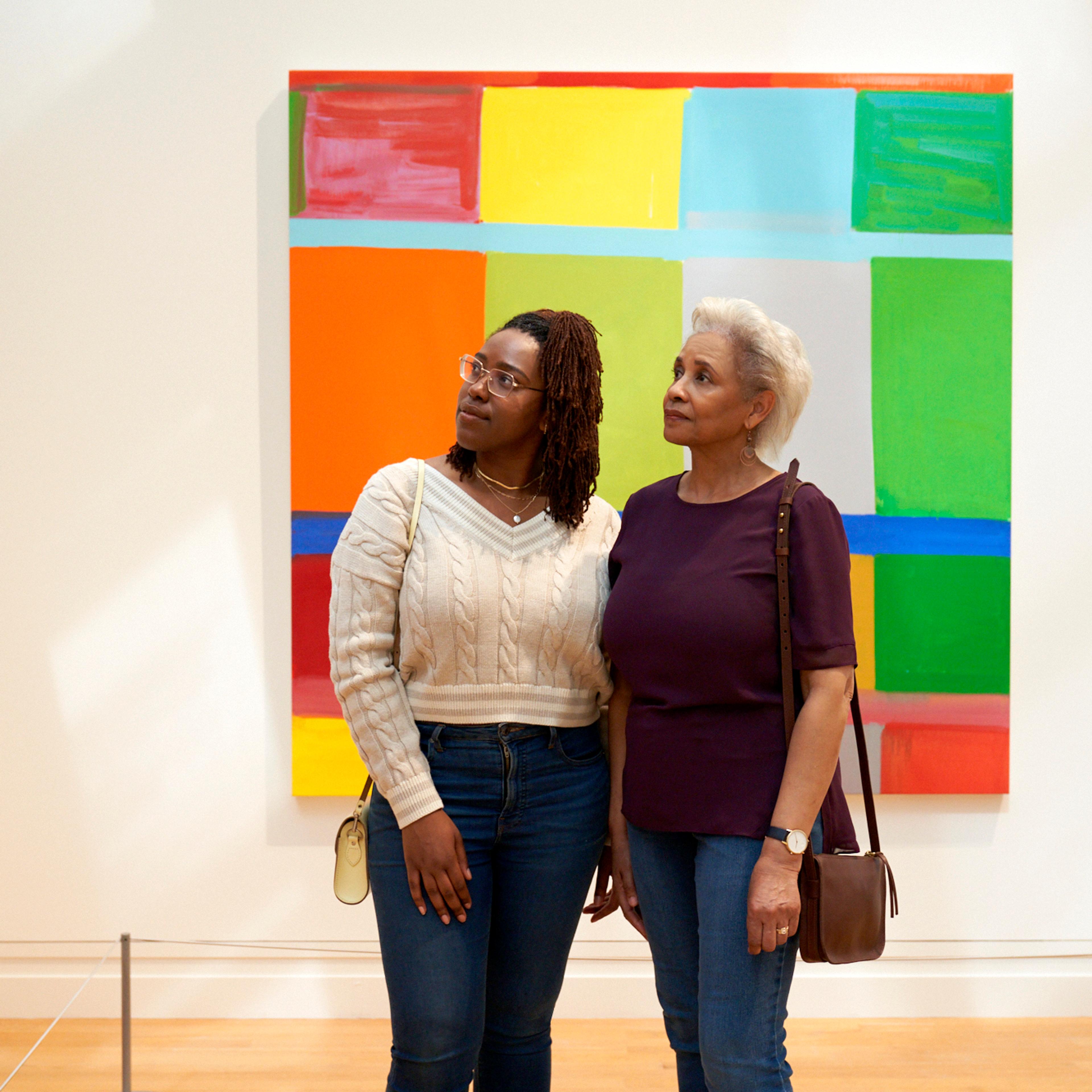 Two Black women, one older one younger, dressed in casual clothing, stop to look at abstract, colorful, work on view in The Met's Modern and Contemporary Galleries.