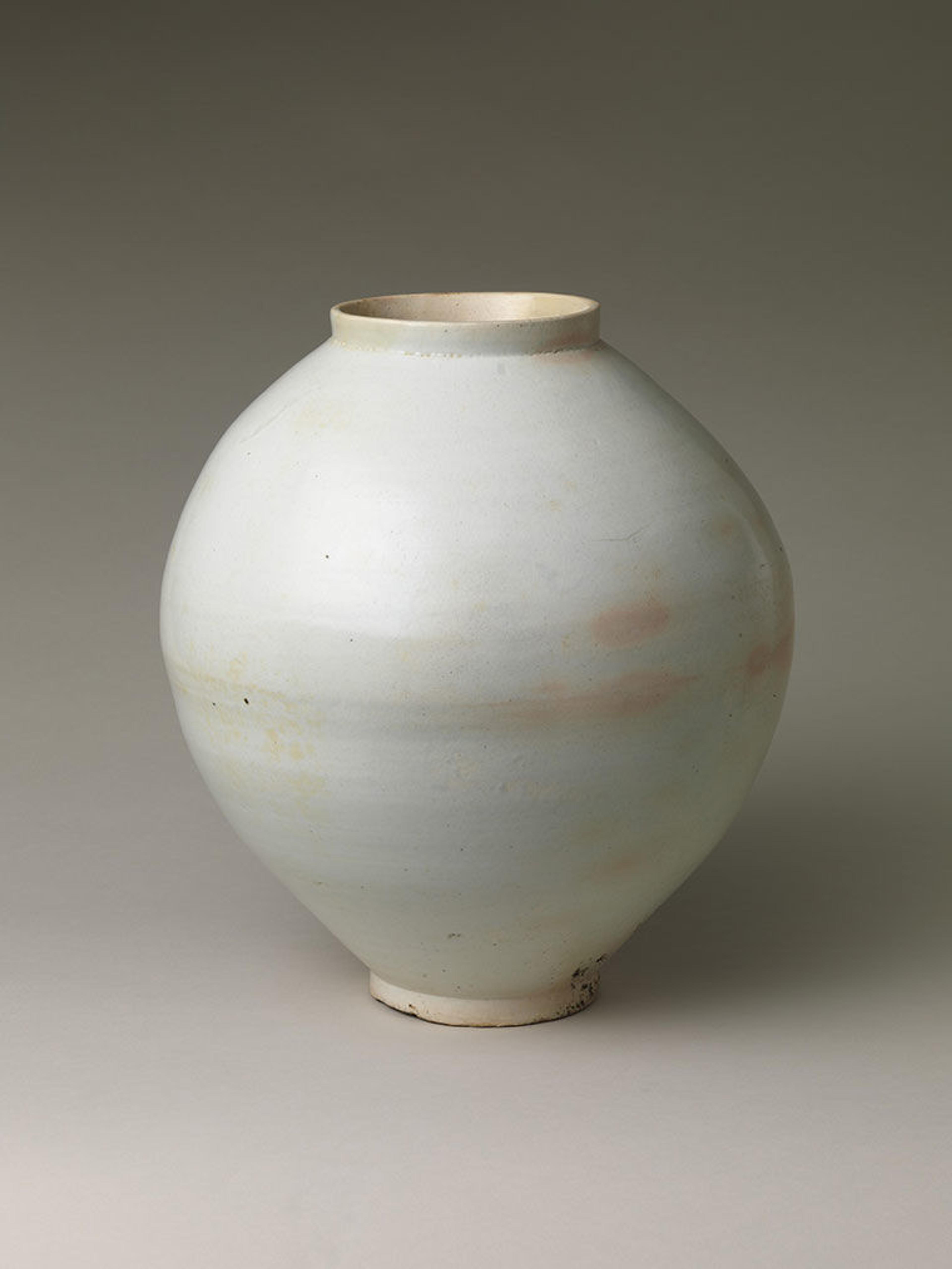 A large, white jar with some peach colored spots around the center