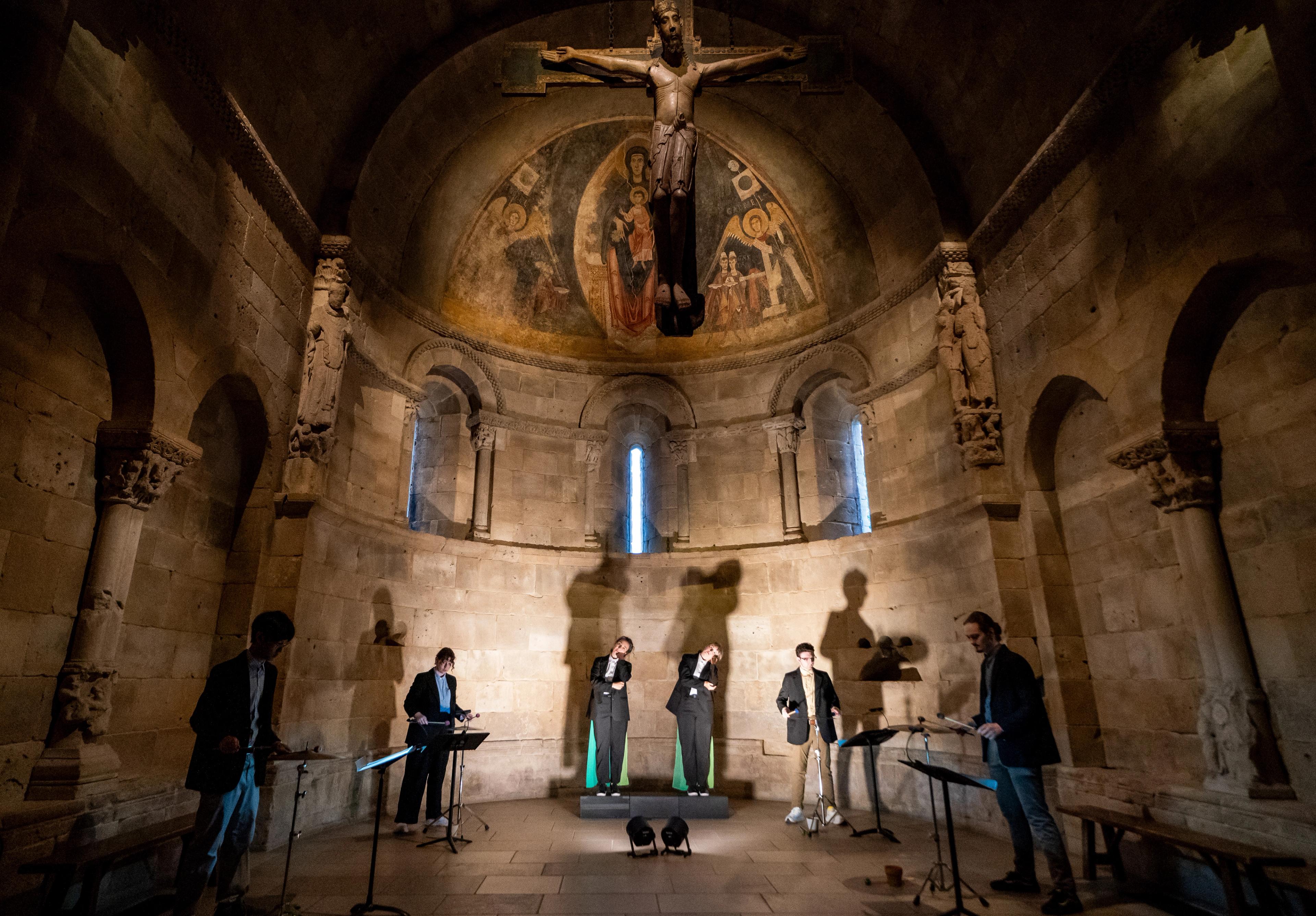 Six percussionists and actors cast tall shadows against the stone walls of the domed Fuentidueña Chapel.